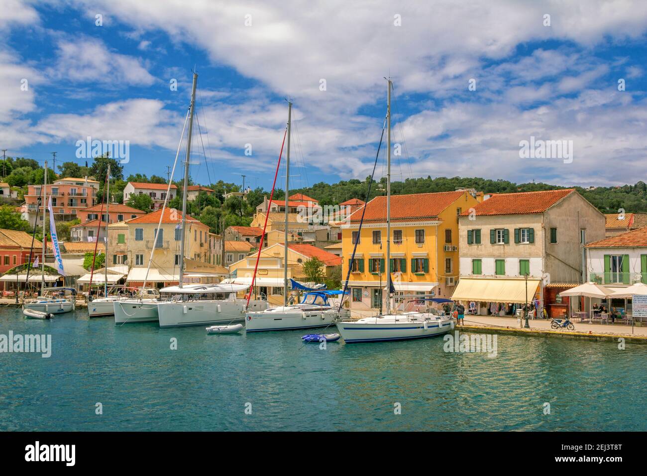 Ile de Paxos, Grèce- 7 mai 2019: Vue sur le magnifique port de Loggos - baie de mer avec l'eau turquoise calme, les navires et les yachts vieilles maisons colorées, ciel bleu Banque D'Images