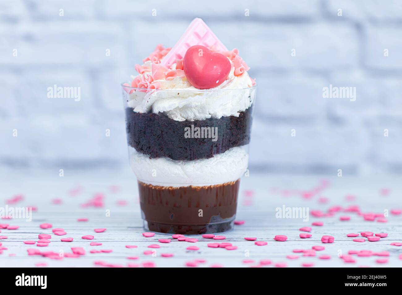 Dessert sucré au chocolat brun et à la crème blanche aérée dans un verre transparent. Le gâteau est décoré de chocolat rose et d'un coeur maurique. Anniversaire Banque D'Images