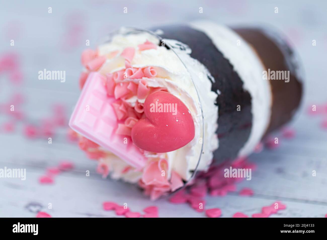 Dessert sucré au chocolat brun et à la crème blanche aérée dans un verre transparent. Le gâteau est décoré de chocolat rose et d'un coeur maurique. Anniversaire Banque D'Images