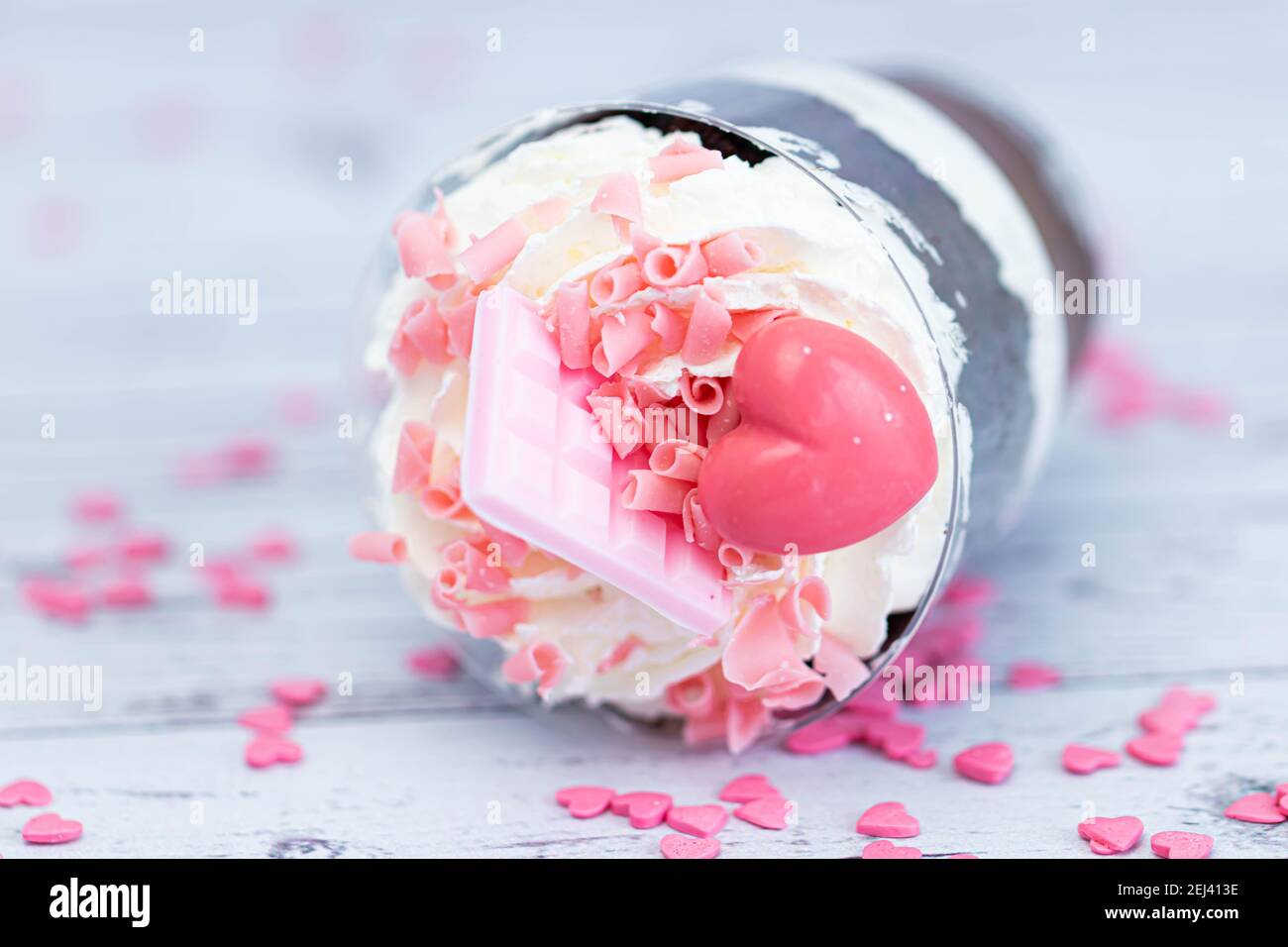 Dessert sucré au chocolat brun et à la crème blanche aérée dans un verre transparent. Le gâteau est décoré de chocolat rose et d'un coeur maurique. Anniversaire Banque D'Images