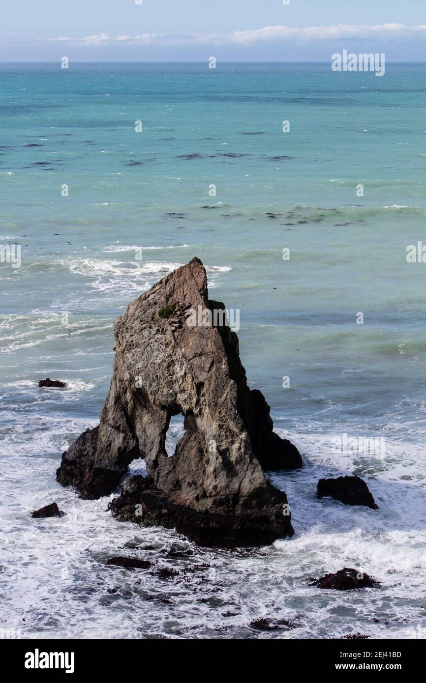 L'océan Pacifique se lave contre une pile de mer accidentée et érodée au large de la côte nord de la Californie, lors d'une belle journée. Banque D'Images