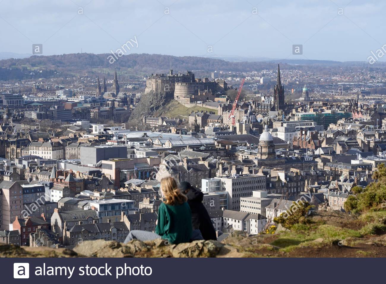 Édimbourg, Écosse, Royaume-Uni. 21 février 2021. Les gens qui profitent du soleil et de l'extérieur dans Holyrood Park. Depuis Salisbury Crags, vue sur le château d'Édimbourg et les toits du centre-ville. Crédit : Craig Brown/Alay Live News Banque D'Images