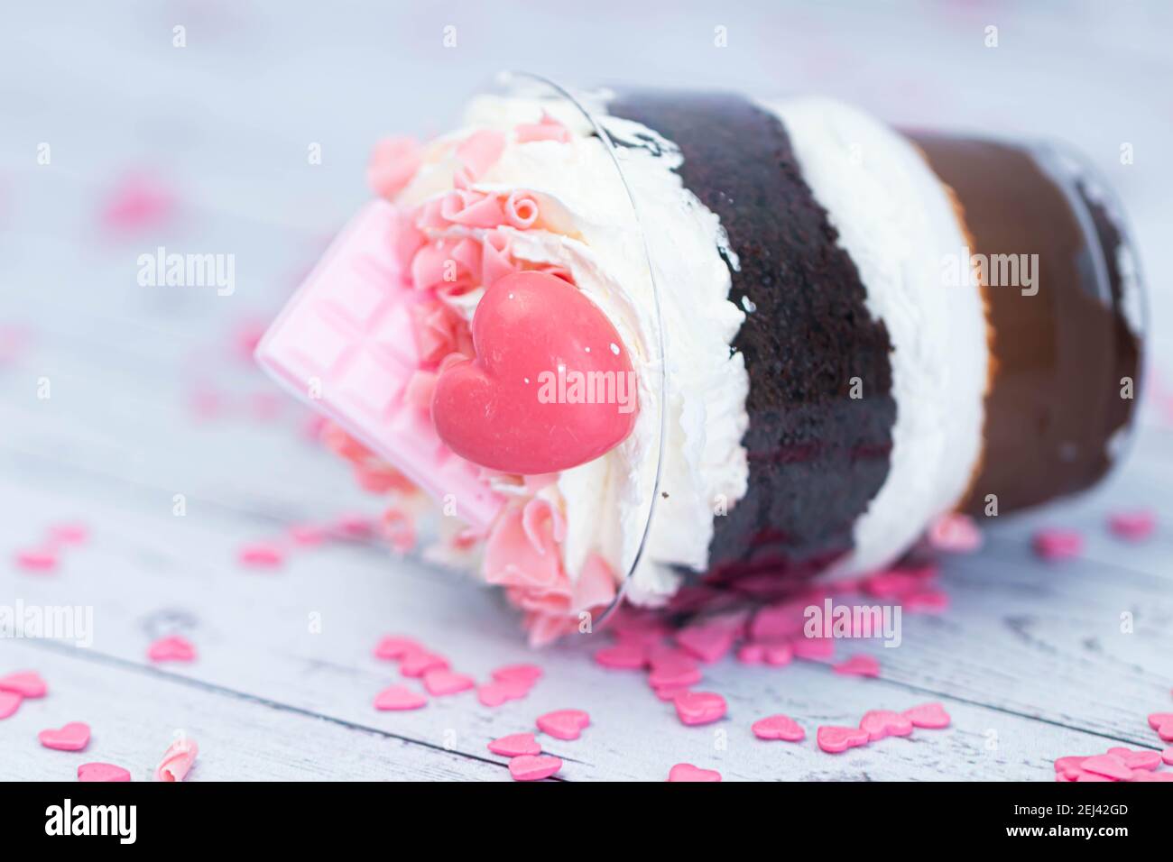 Dessert sucré au chocolat brun et à la crème blanche aérée dans un verre transparent. Le gâteau est décoré de chocolat rose et d'un coeur maurique. Anniversaire Banque D'Images