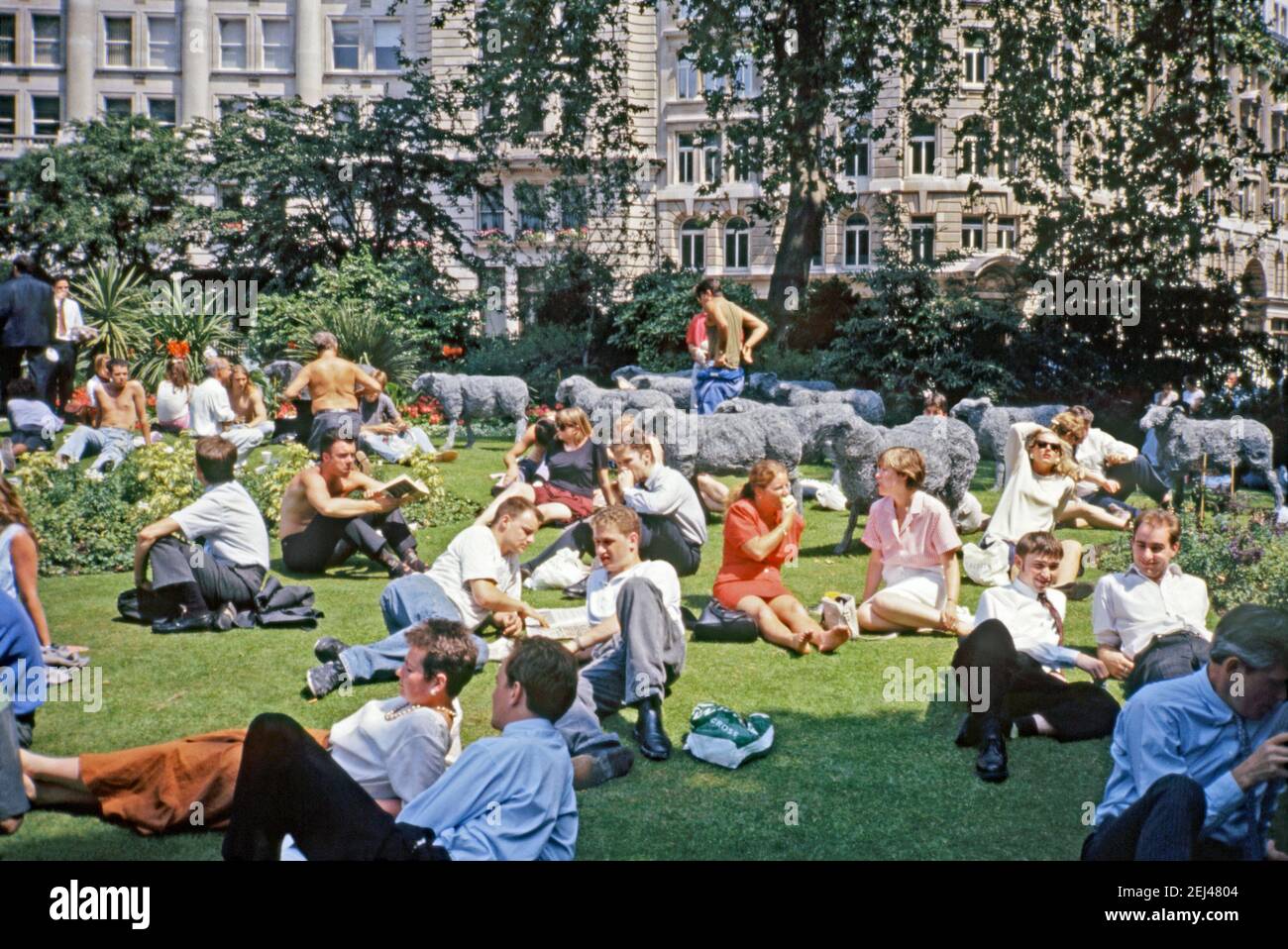Une œuvre de 1991, Sophie Ryder’s ‘heep’, située parmi les travailleurs bénéficiant du soleil dans un espace public ouvert ensoleillé dans la City de Londres, Angleterre, Royaume-Uni 1993. Cette œuvre faisait partie de l’« Art in the City » de 1993 et visait à faire de la sculpture une place parmi les espaces verts et l’architecture distinctive de la City de Londres. Sophie Ryder (1963) est une sculptrice britannique. Elle est surtout connue pour ses énormes sculptures en fil de fer. Les moutons sont souvent présents dans son travail. Banque D'Images