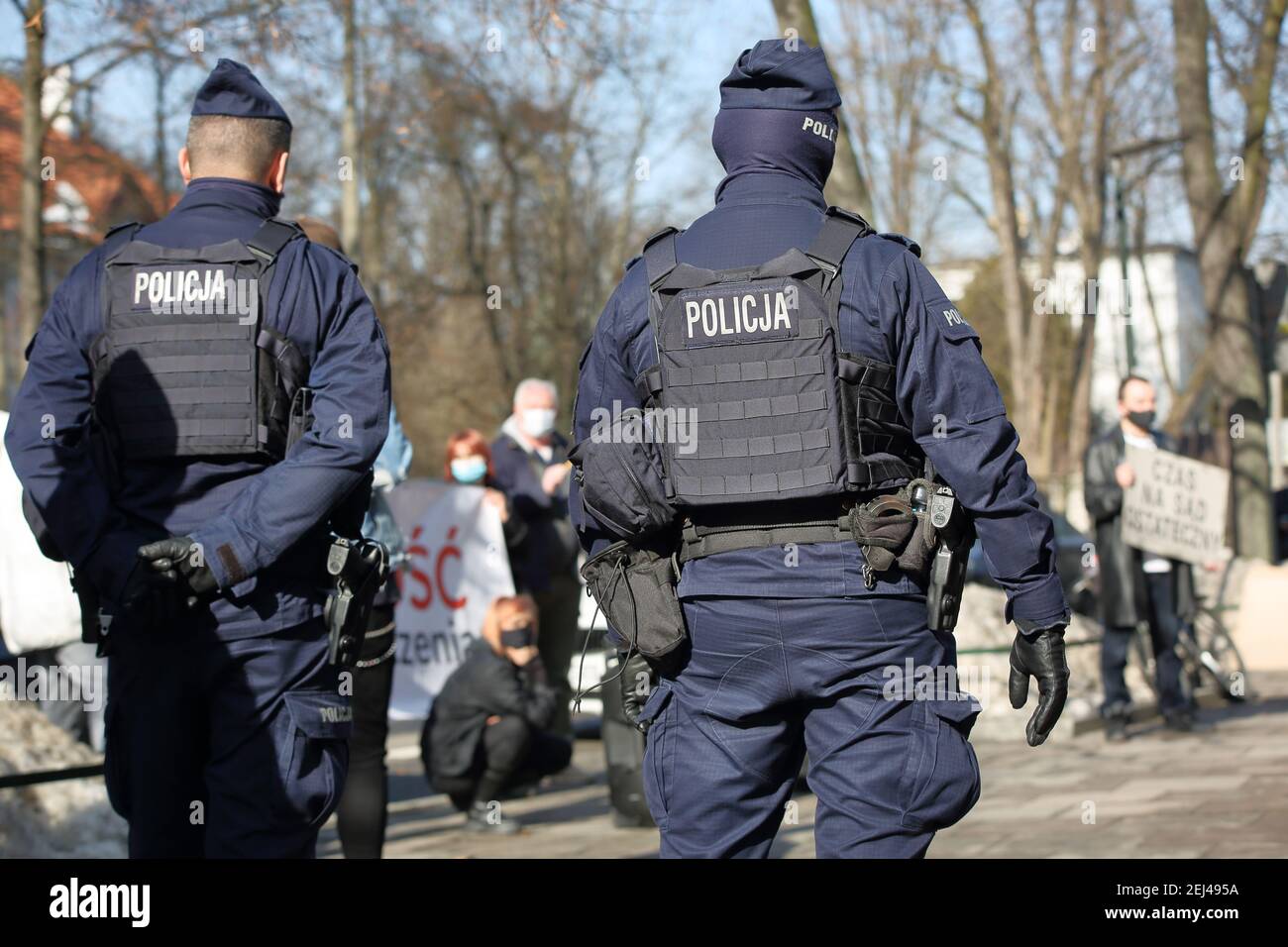 Deux policiers en uniforme, armés, se tiennent dans la rue pour observer les manifestants Banque D'Images