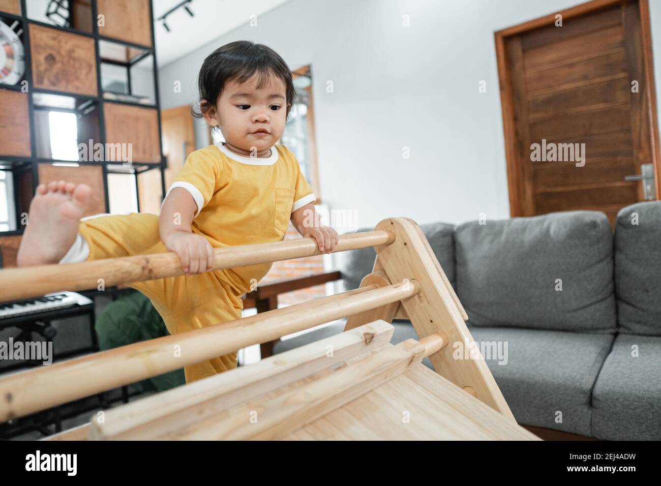 Bebe Essayant De Lever Ses Jambes Tout En Grimpant Sur Le Pikler Jouet Triangle Dans La Salle De Sejour Photo Stock Alamy