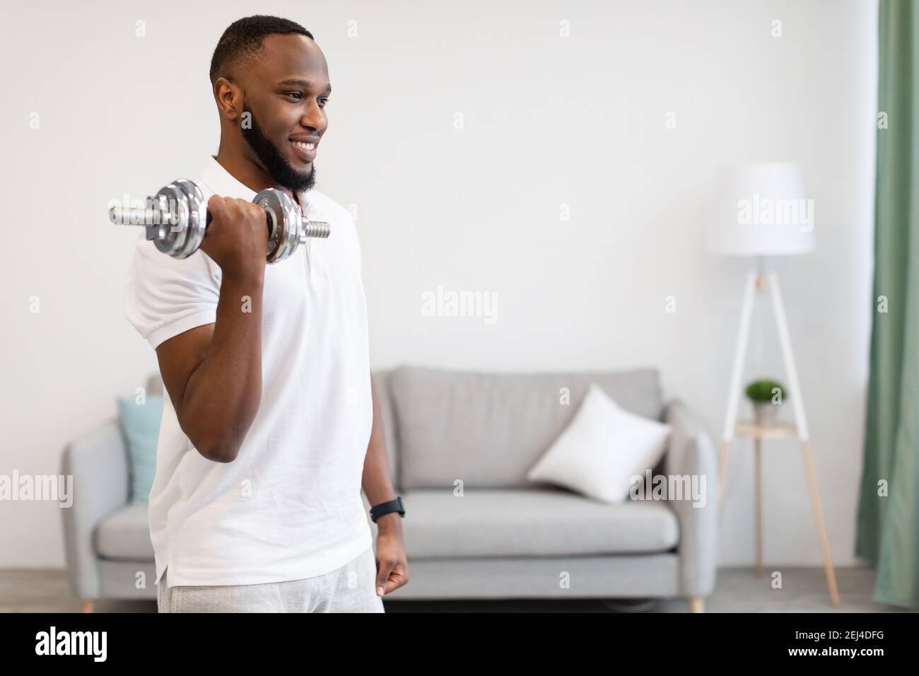 Athlétique Africain américain Guy s'exerçant avec Dumbbell debout à la maison Banque D'Images