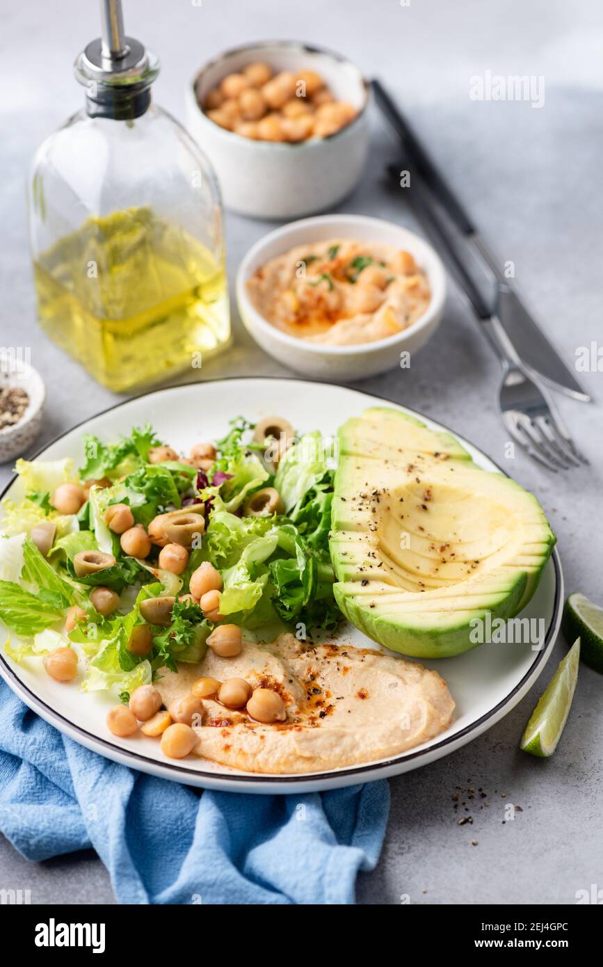 Bol à salade avec houmous de pois chiches, légumes verts et avocat. Salade végétalienne saine servie avec de l'huile d'olive Banque D'Images