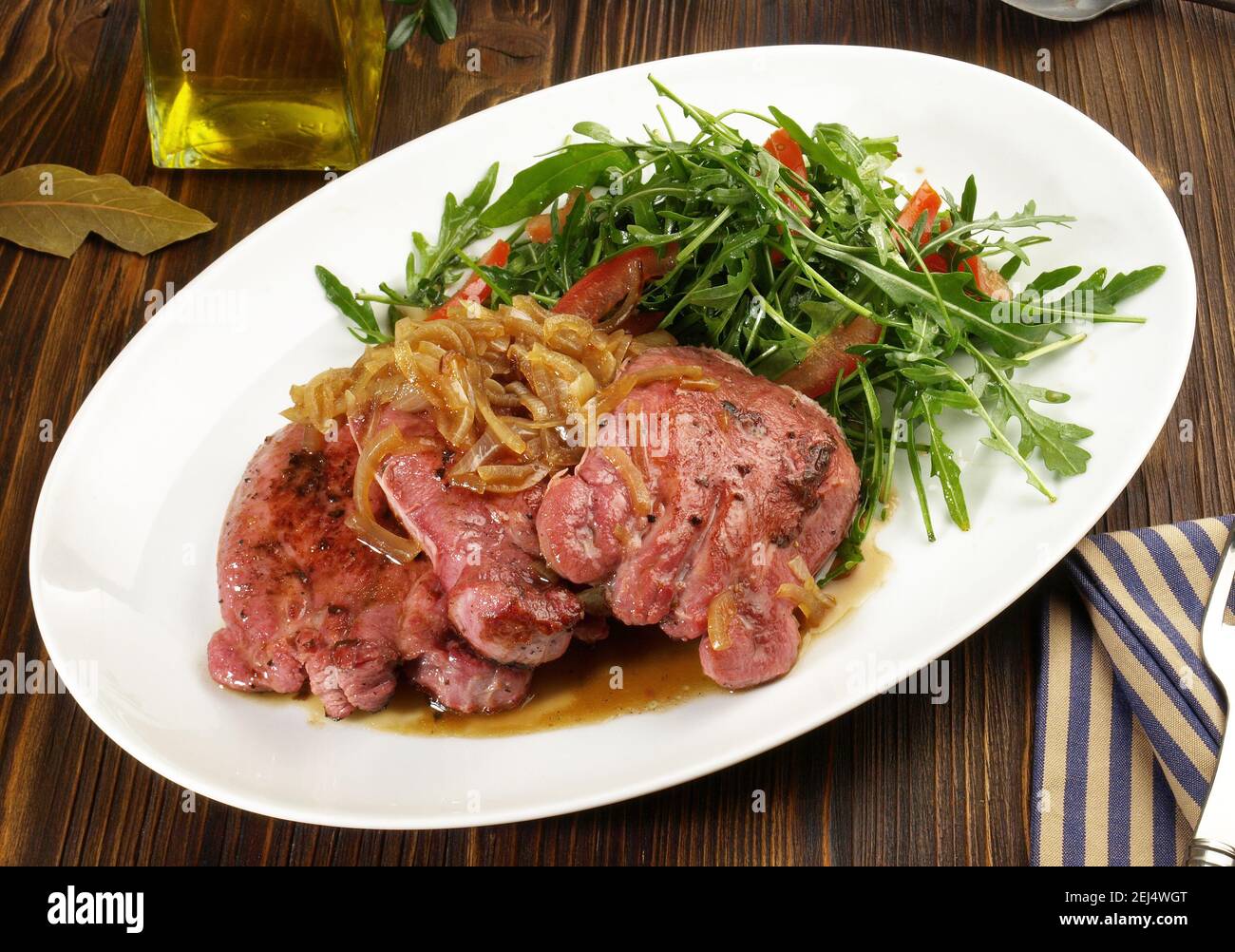 Tranches de viande de langue de veau cuite bouillie avec oignons rôtis et Salade sur fond de bois Banque D'Images