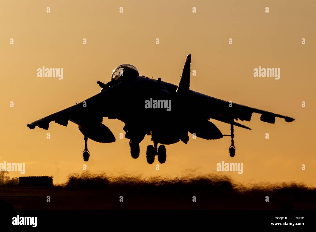 La silhouette d'un bombardier de chasseurs Harrier débarque au coucher du soleil avec un ciel orange Banque D'Images