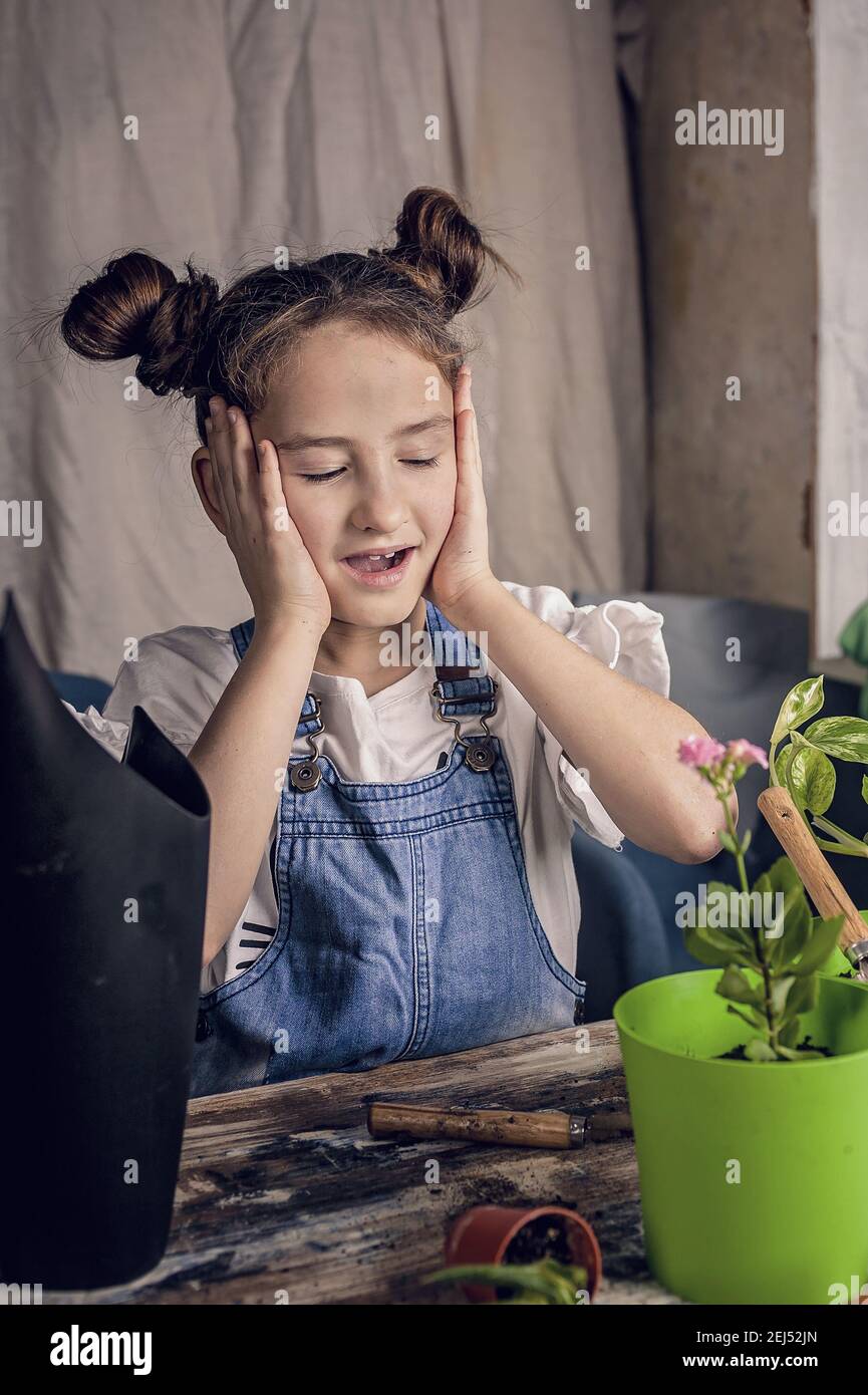 mignon surprise fille regarde la plantule dans un pot de fleurs.printemps jardinage à la maison. origine caucasienne. vue de face. plan vertical. Banque D'Images