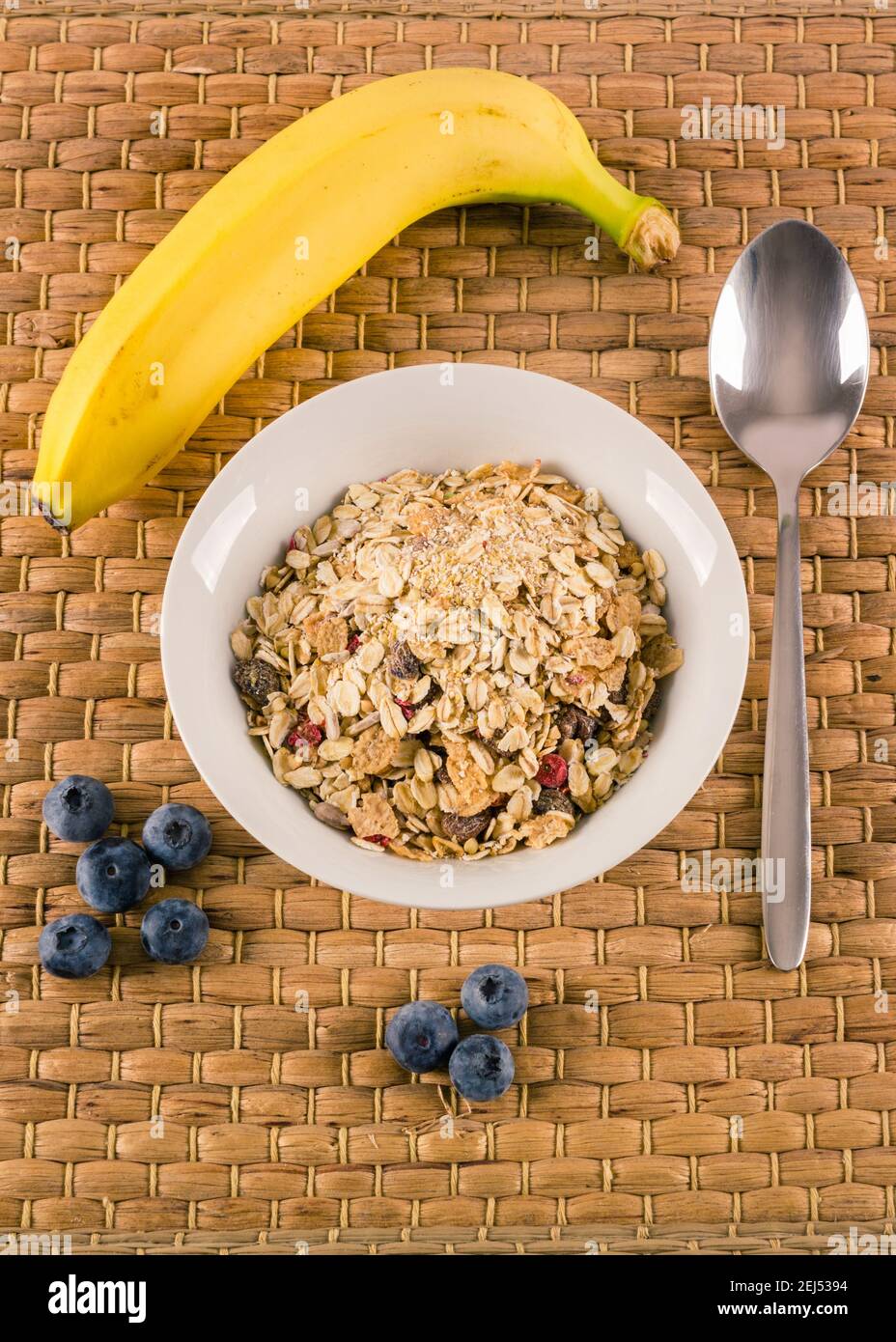 Petit déjeuner sain composé de céréales, de bananes et de myrtilles avec cuillère à part Banque D'Images