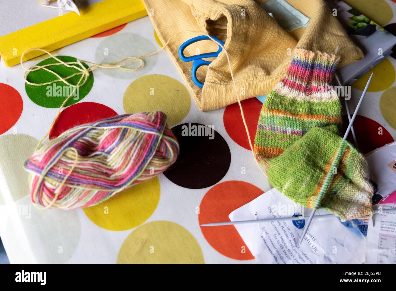 Balle de laine assise sur une table avec des aiguilles à tricoter, chaussette partiellement tricotée, fil artisanal faisant chaud laine chaussettes de laine faites à la main pendant la pandémie de covid Royaume-Uni Banque D'Images