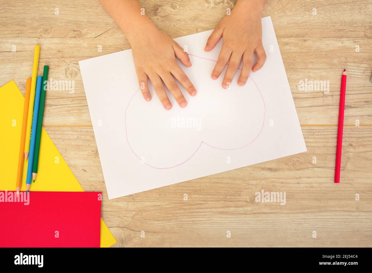Vue de dessus. Les mains des enfants ont peint un coeur sur papier, carte à faire soi-même. Concept pour le 8 mars, Saint-Valentin, fête des mères Banque D'Images