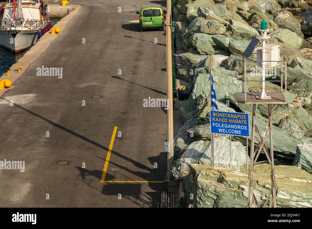 Folegnadros, Grèce- 26 septembre 2020 : vue sur le port de l'île de Folegandros. Voiture verte garée sur la route. Brise-lames en pierre le long de la route. Banque D'Images