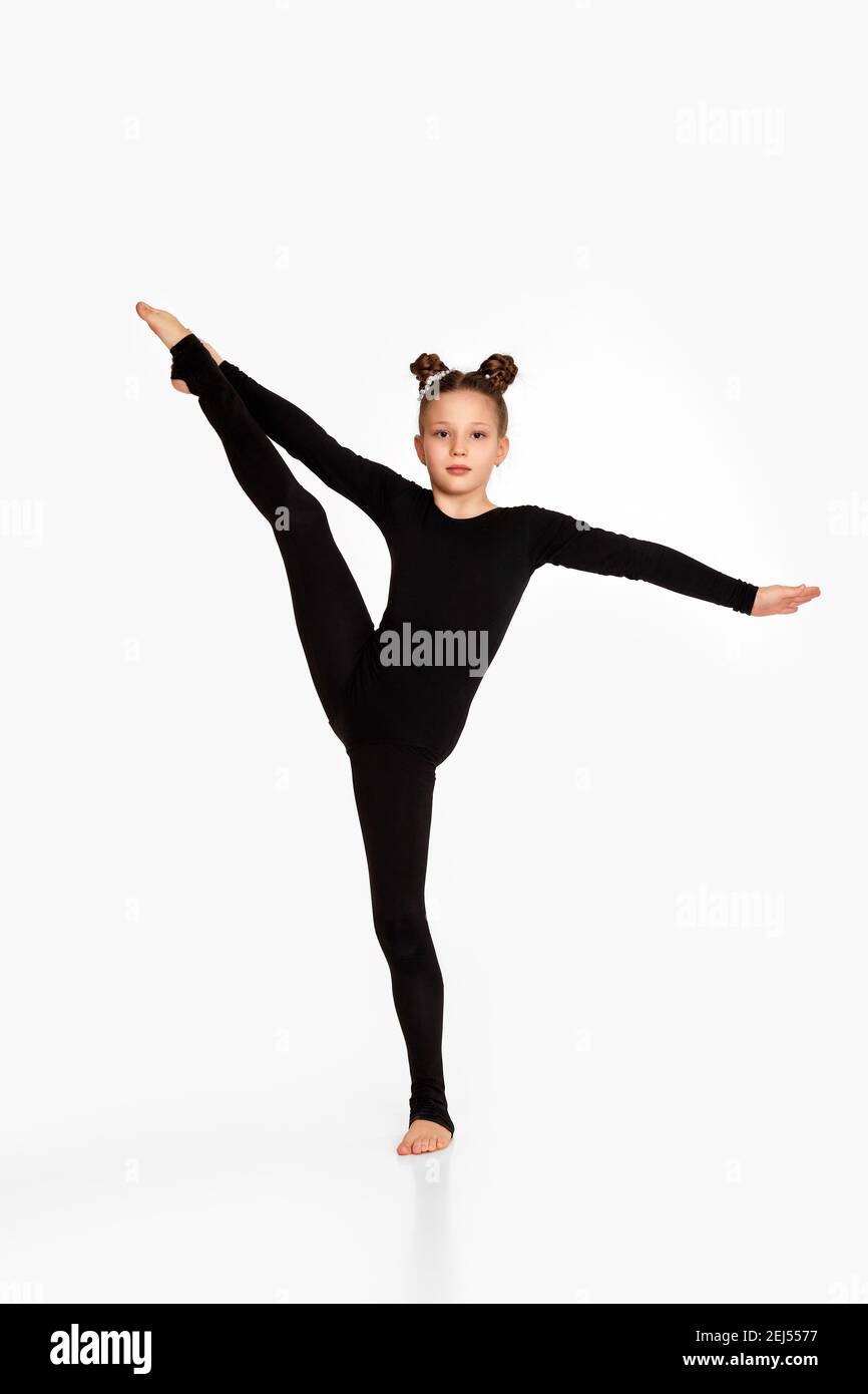 adorable petite fille fille en noir sportswear faire stretching. gymnastique Banque D'Images