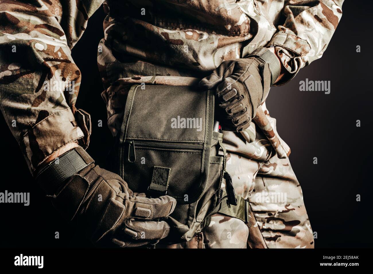Photo d'un soldat en uniforme de camouflage et gants tactiques utilisant un sac  de jambe sur fond noir Photo Stock - Alamy
