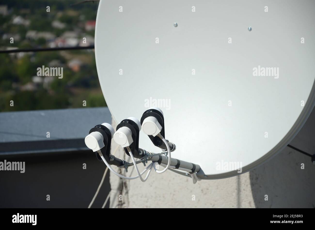 Parabole satellite blanche avec trois convertisseurs montés sur le mur en  béton du toit du bâtiment résidentiel. Publicité à la télévision par  satellite Photo Stock - Alamy