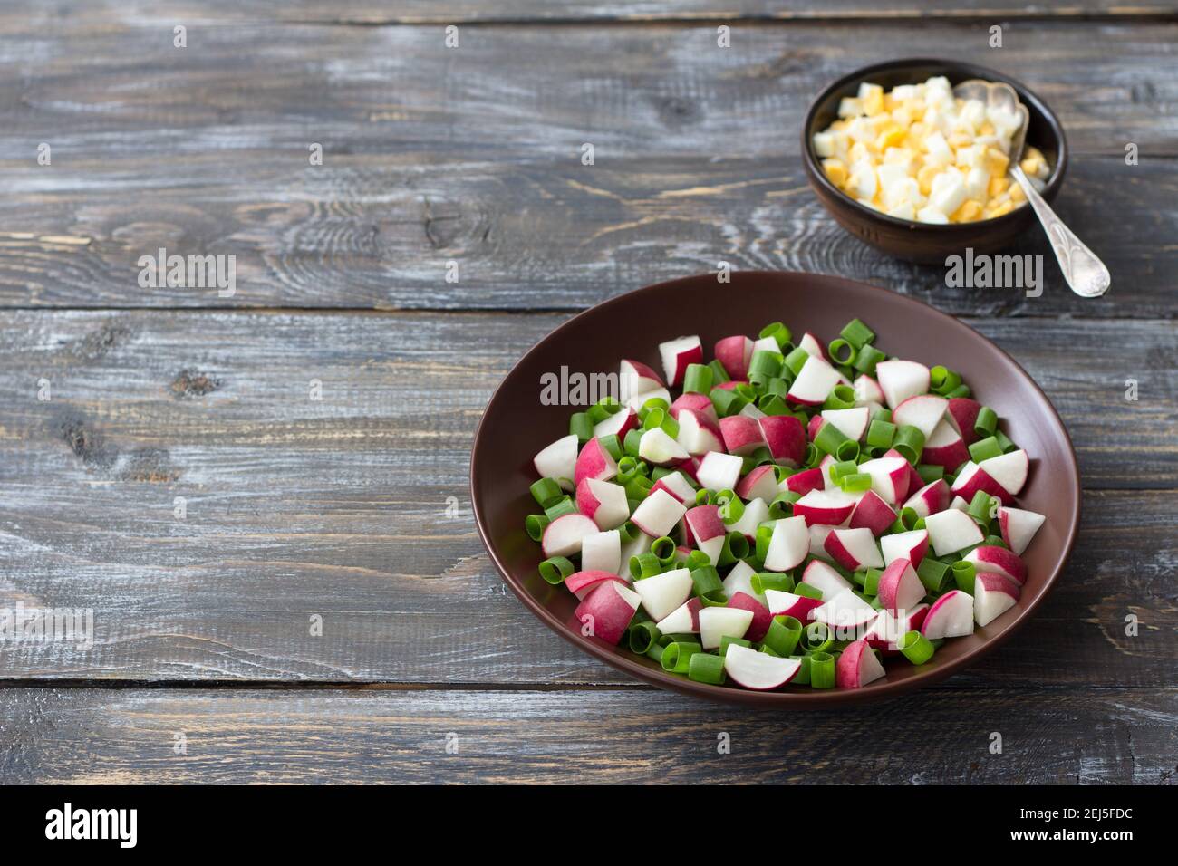 Salade de radis frais avec oignons verts et œufs durs sur fond de bois, style rustique. Délicieux plats faits maison Banque D'Images
