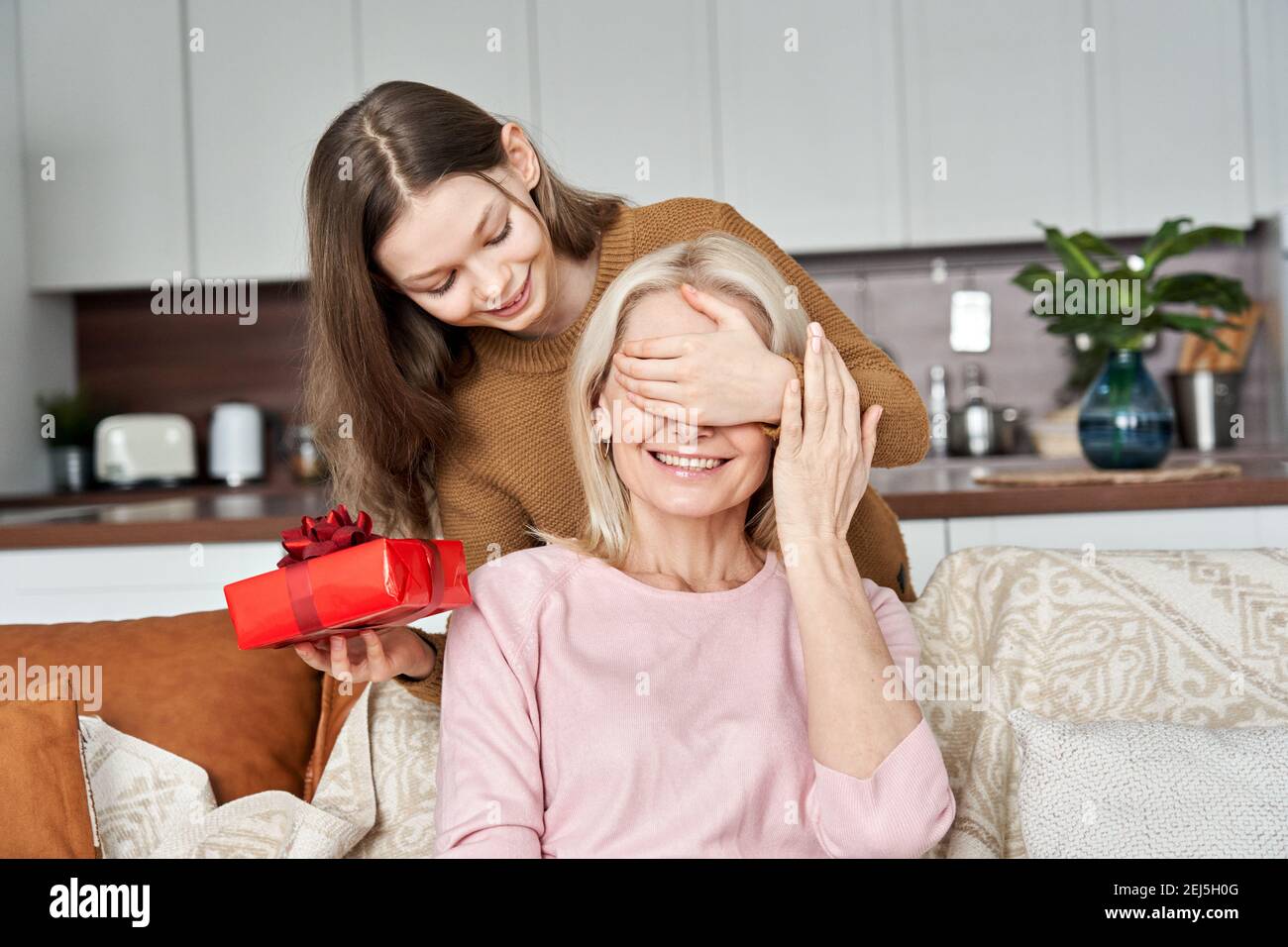 Mignon adolescent fille tenant boîte cadeau salutation maman le jour de la fête des mères. Banque D'Images