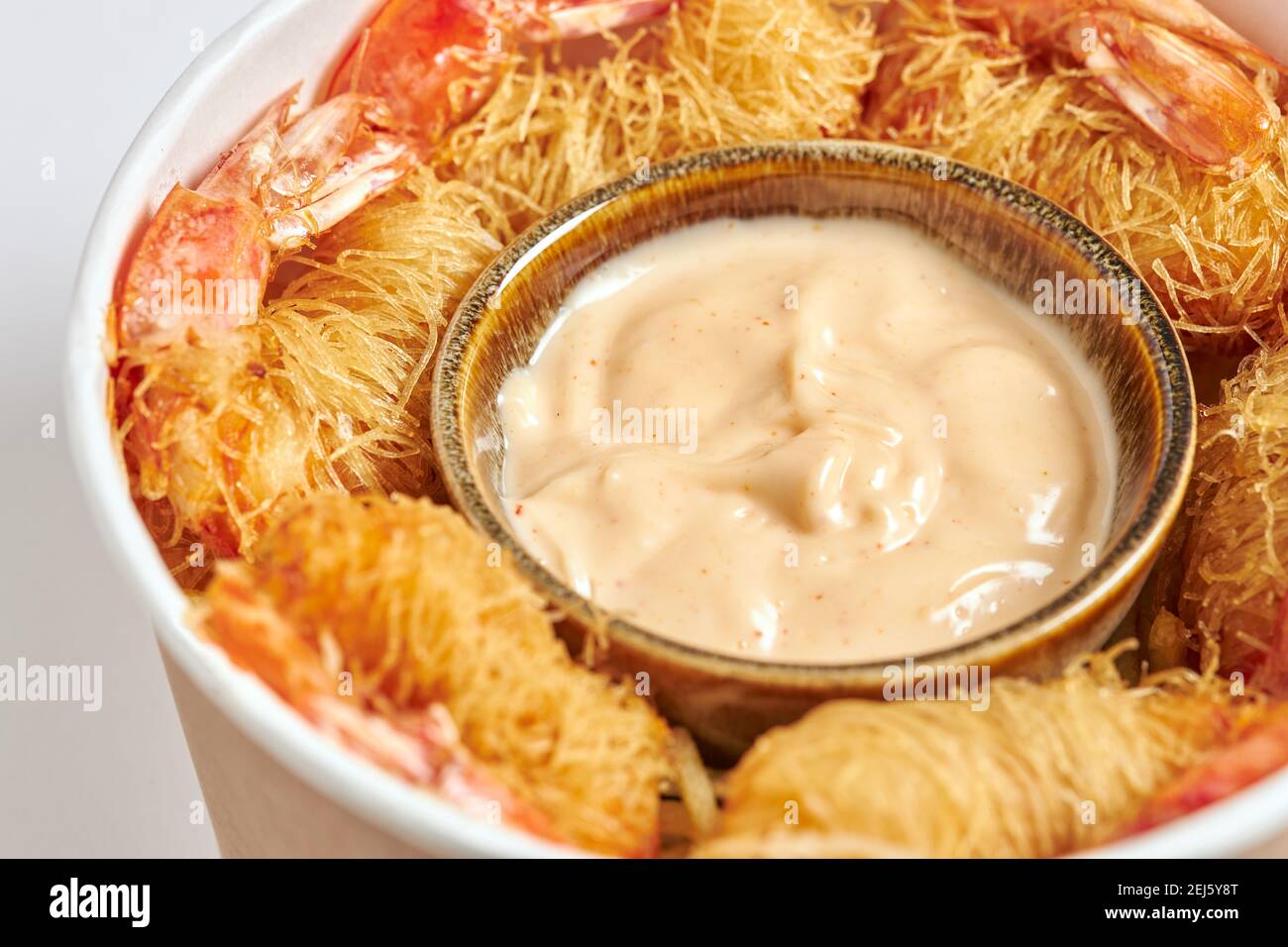 Gros plan d'un cube de crevettes frites enveloppées de pâtes Kataifi et servies avec une sauce dragon. Banque D'Images