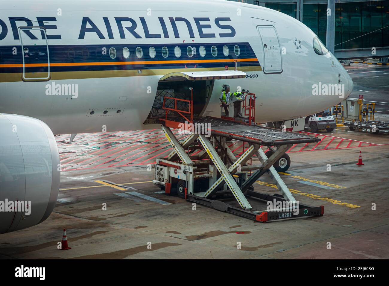 Un chargeur ULD soulevant un dispositif de charge unitaire (ULD) de Un tablier s'étend jusqu'à une baie de fret d'avions d'un Singapour Compagnie aérienne à l'aéroport Changi de Singapour Banque D'Images