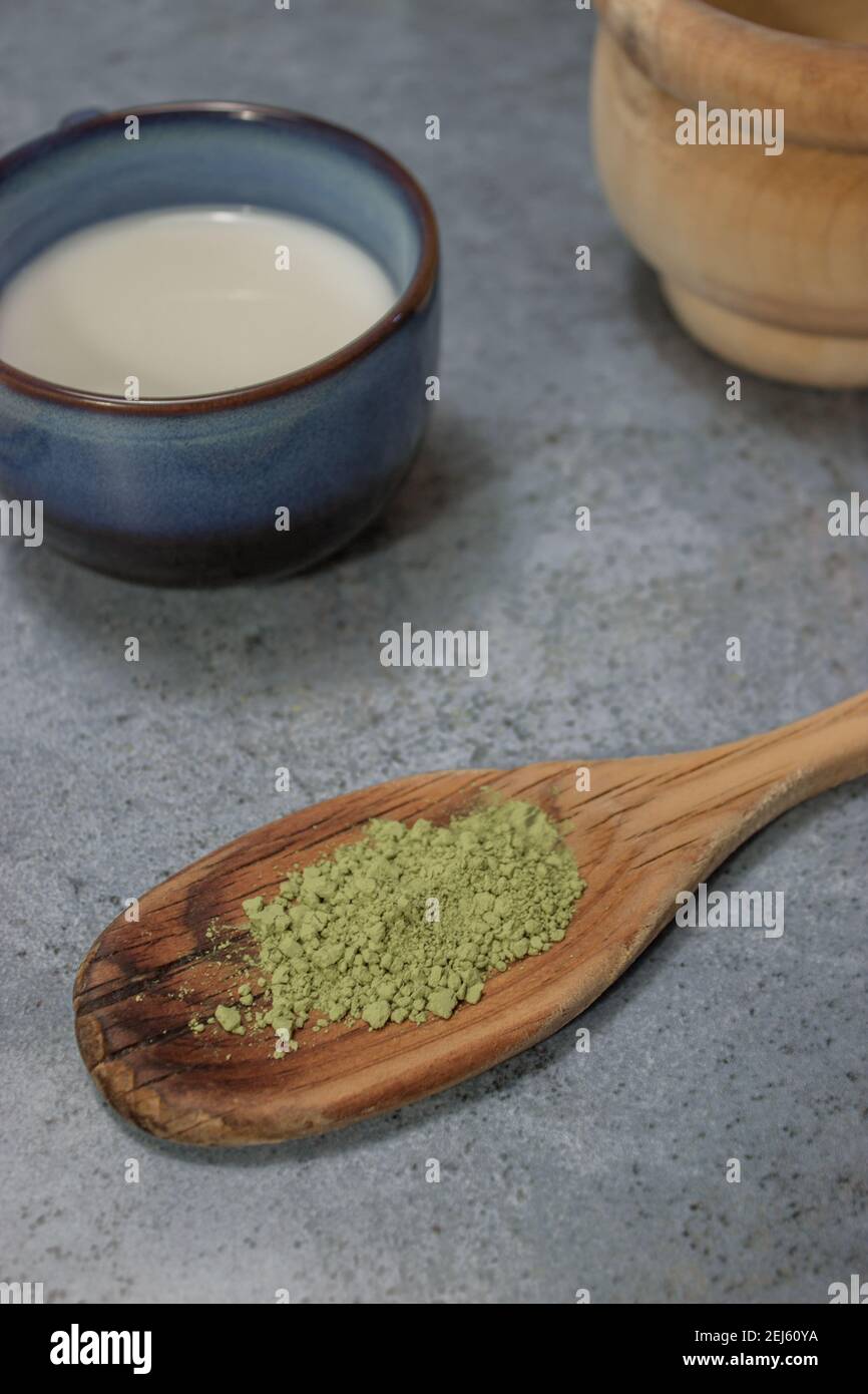 Vue de dessus verticale thé matcha en poudre saine sur une cuillère en bois avec une tasse de lait et de sucre dans un fond de pierre grise. Le concept de thé vert japonais. Banque D'Images