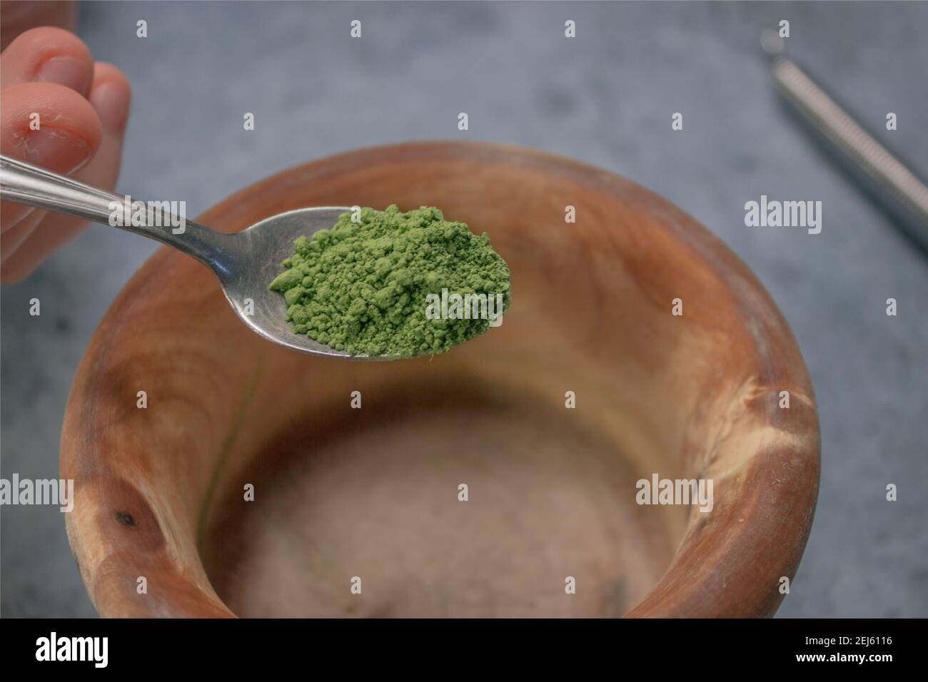 Image verticale de la poudre de thé matcha verser dans un bol en bois sur fond de pierre grise. Le concept de thé vert japonais. Préparation du thé Matcha ingrédient 2021. Banque D'Images