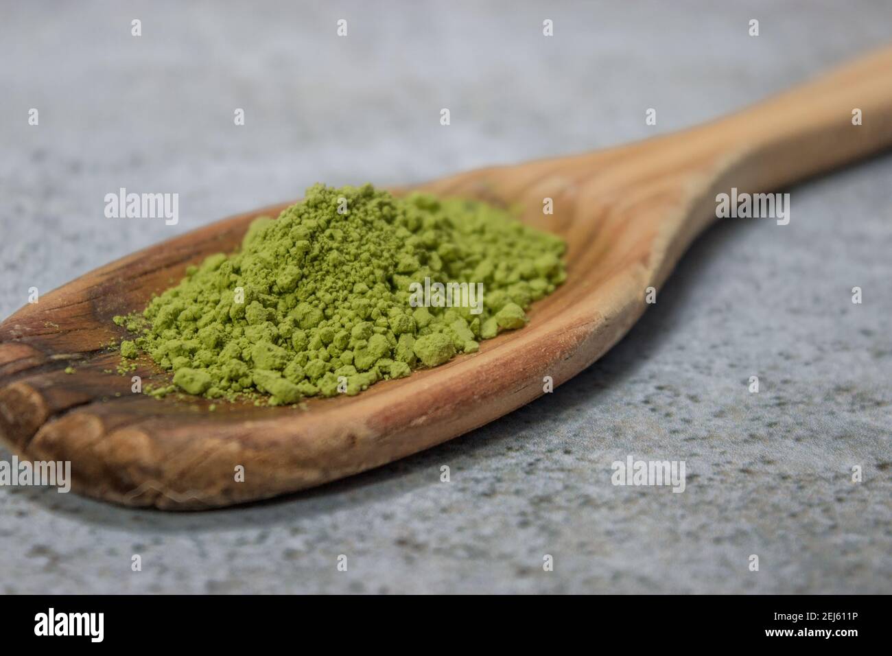 Gros plan de la poudre de thé matcha sur une cuillère en bois sur fond de pierre grise. Le concept de thé vert japonais. Préparation du thé Matcha ingrédient 2021. Banque D'Images