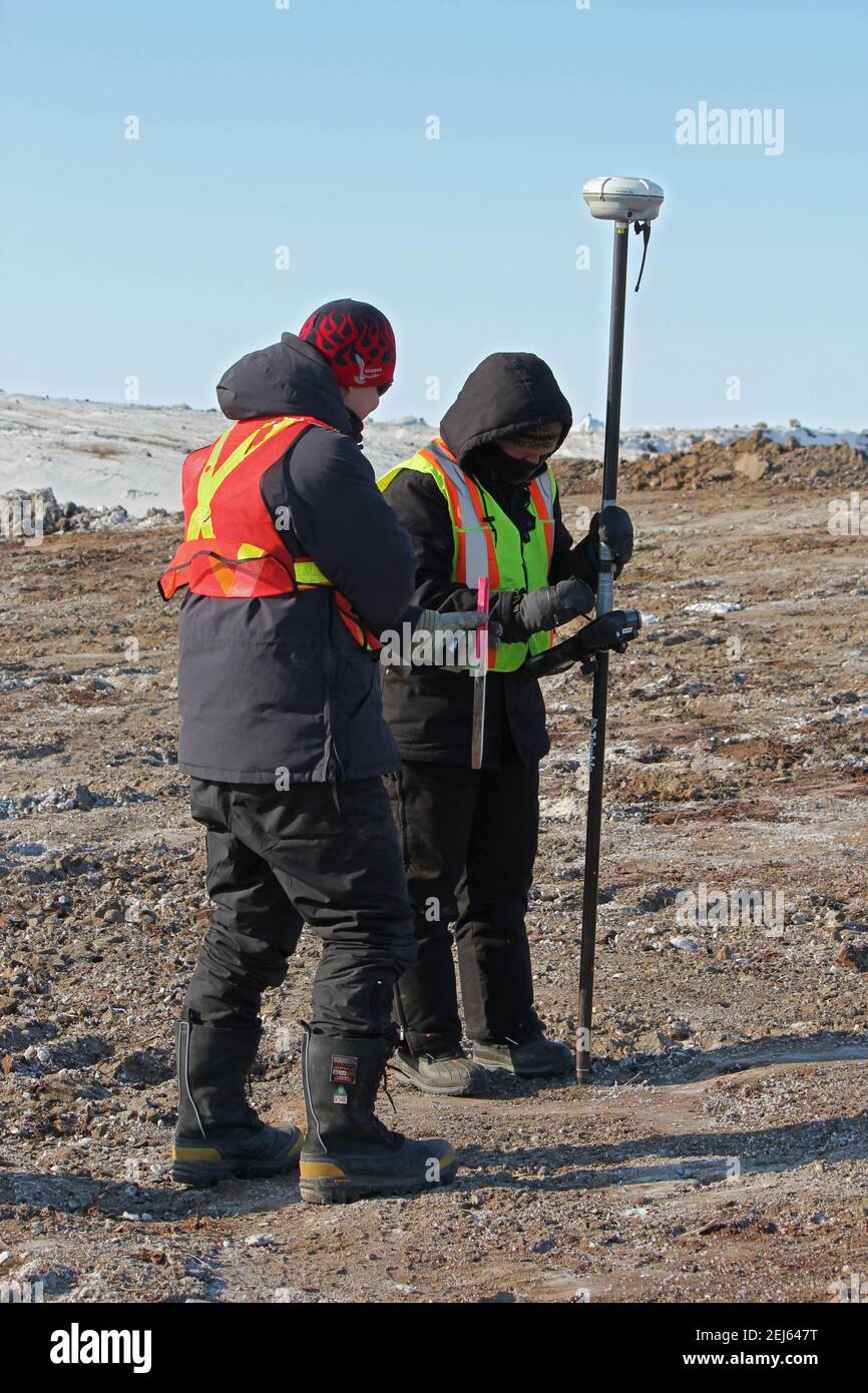 Deux arpenteurs qui travaillent sur la route Inuvik-Tuktoyaktuk pendant la construction hivernale, dans les Territoires du Nord-Ouest, dans l'Arctique canadien. Banque D'Images