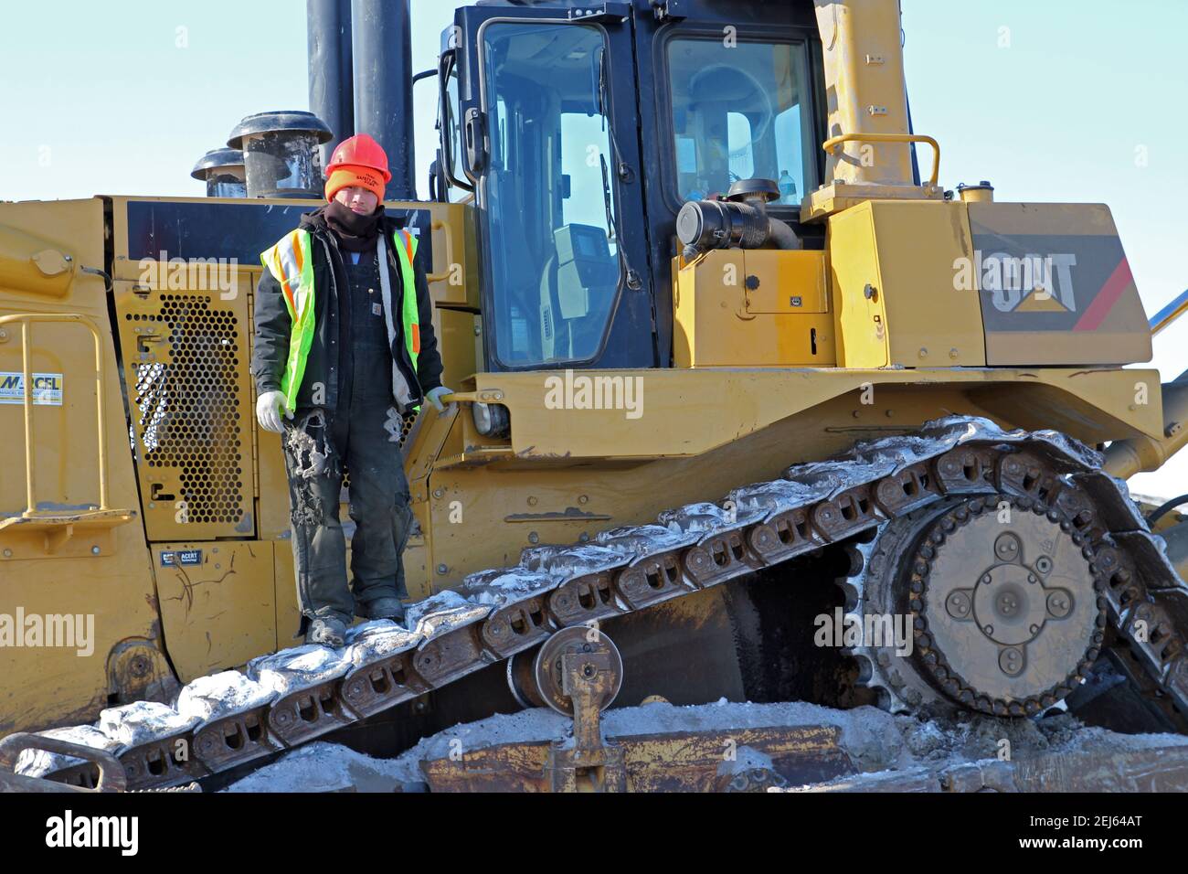 Opérateur d'équipement lourd autochtone debout sur un bulldozer, construction de la route Inuvik-Tuktoyaktuk, Territoires du Nord-Ouest, Arctique canadien. Banque D'Images
