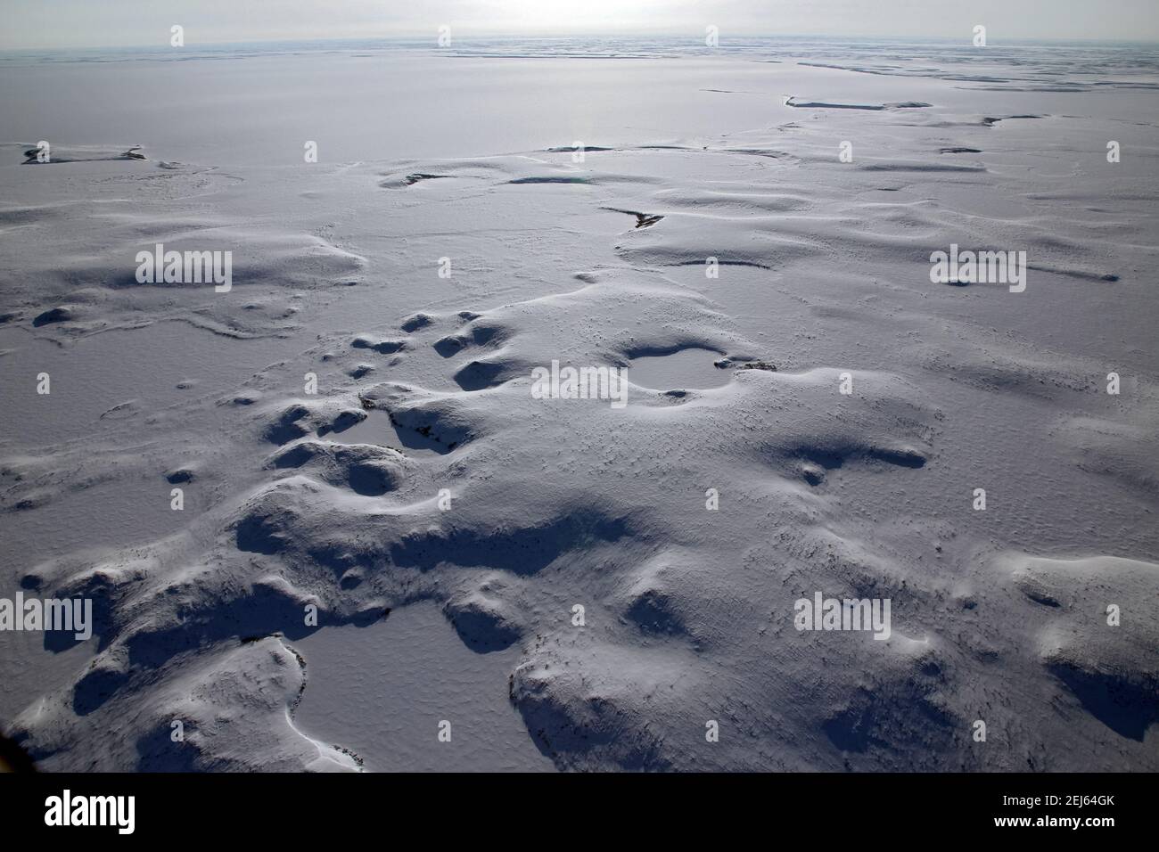Vue aérienne en hiver du paysage gelé de la toundra arctique, recouvert de neige, près de Tuktoyaktuk, Territoires du Nord-Ouest, Canada. Banque D'Images
