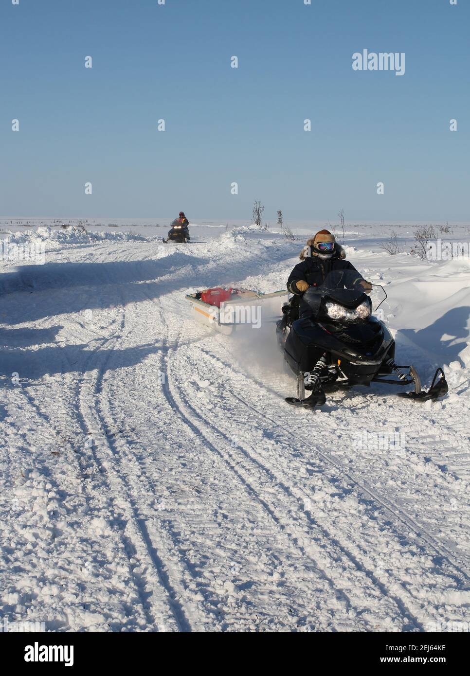 Deux travailleurs de motoneiges pendant la construction hivernale de la route Inuvik-Tuktoyaktuk, Territoires du Nord-Ouest, dans l'Arctique canadien. Banque D'Images