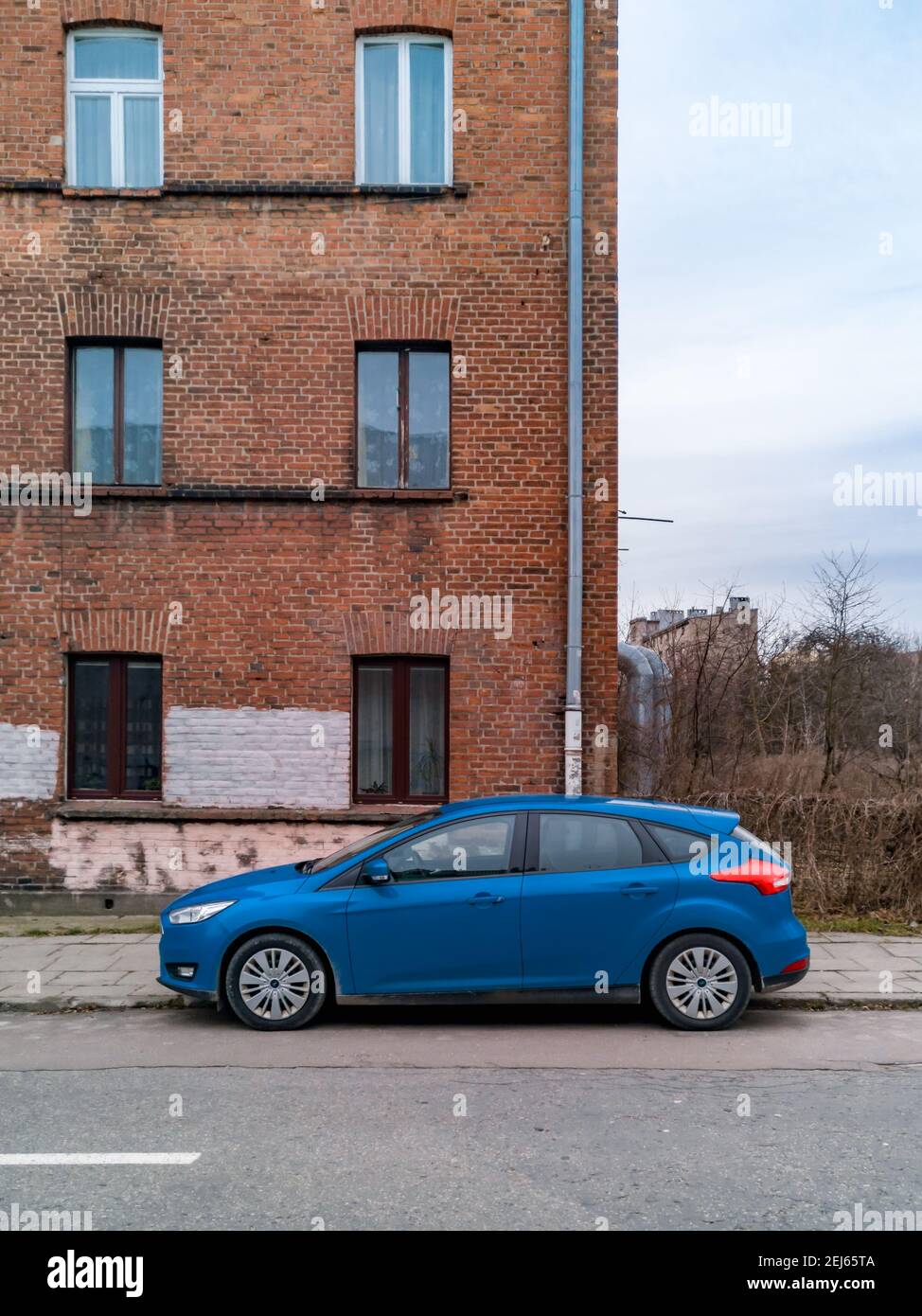 Lodz, Pologne - février 22 2020 voiture bleue située en face de l'ancien bâtiment en briques rouges Banque D'Images