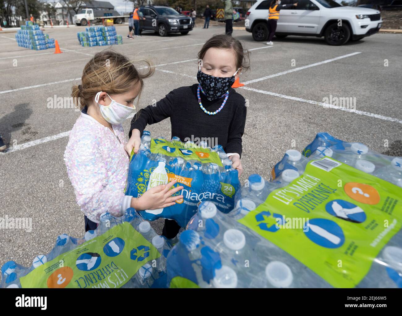 Oak Hill, Texas, États-Unis. 21 février 2021. PEYTON SOMERS, 6 ans, et son ami BLAKE ANDERSON, 6 ans, ont aidé à faire passer l'eau à l'ouest désespéré du comté de Travis, TX résidents hors de l'eau du robinet pendant plusieurs jours en raison de la tempête de neige dévastatrice du Texas la semaine dernière. Les conducteurs n'ont reçu qu'un seul dossier par voiture après trois heures d'attente le 21 février 2021. Crédit : Bob Daemmrich/ZUMA Wire/Alay Live News Banque D'Images