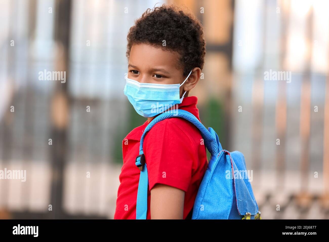 Petit garçon afro-américain dans un masque médical près de l'école. Épidémie de coronavirus Banque D'Images