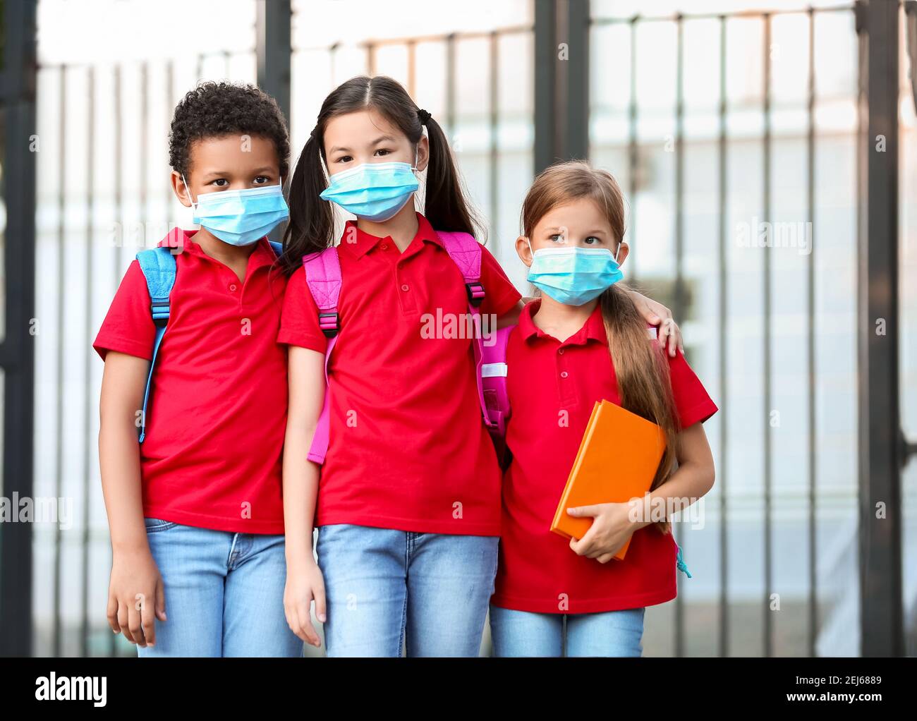 Petits élèves dans des masques médicaux près de l'école. Épidémie de coronavirus Banque D'Images