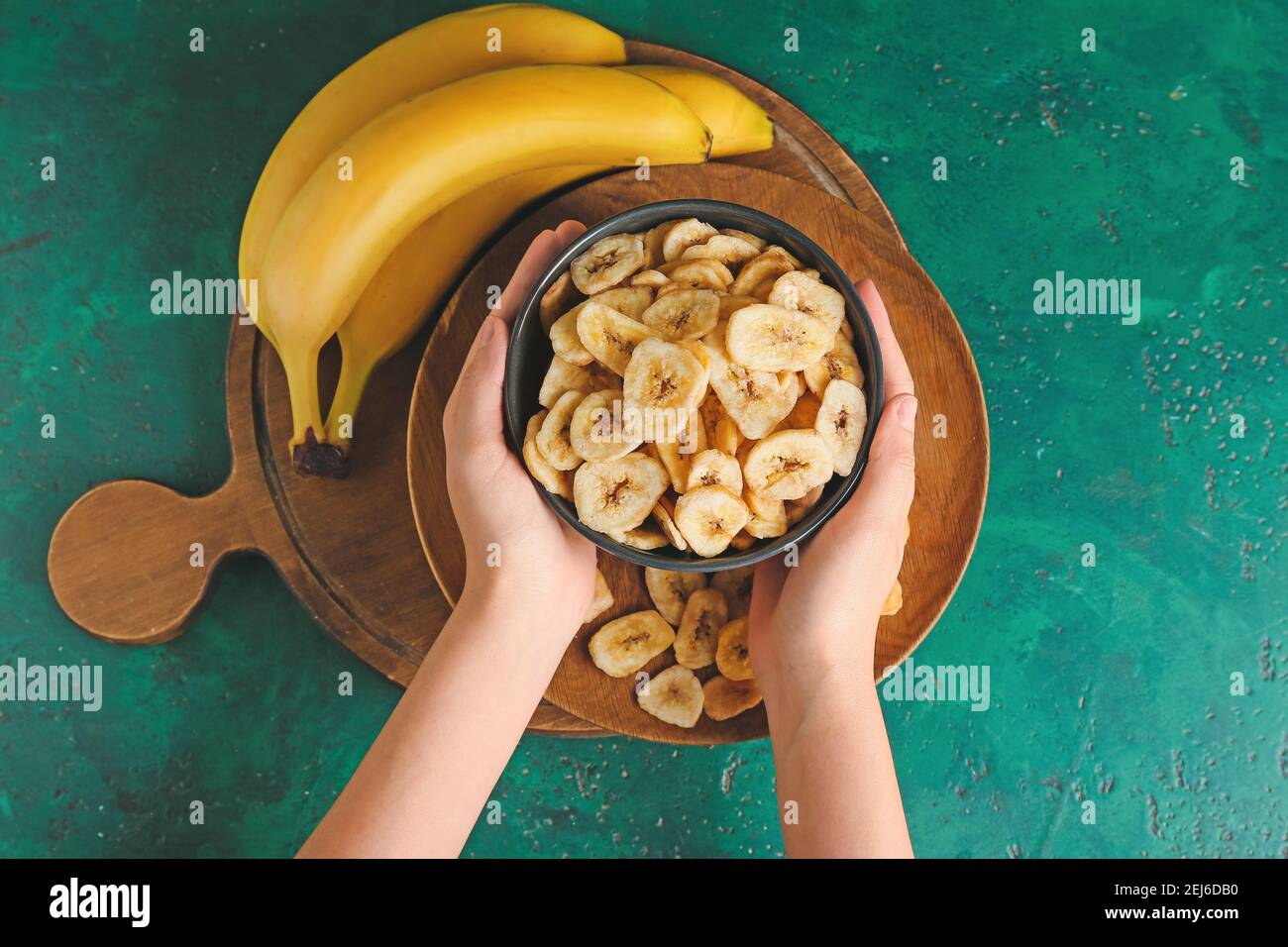 Femme tenant un bol avec des chips de banane croustillantes sur fond de couleur Banque D'Images