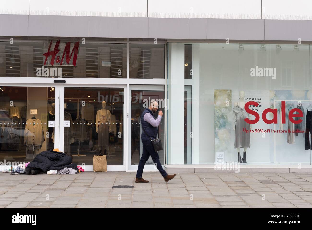 Un homme à l'extérieur de l'entrée du magasin H&M, affiche de solde sur la  fenêtre Photo Stock - Alamy