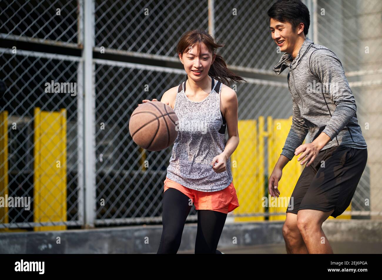 jeune asiatique couple petit ami jouant au basket-ball pour s'amuser court extérieur Banque D'Images