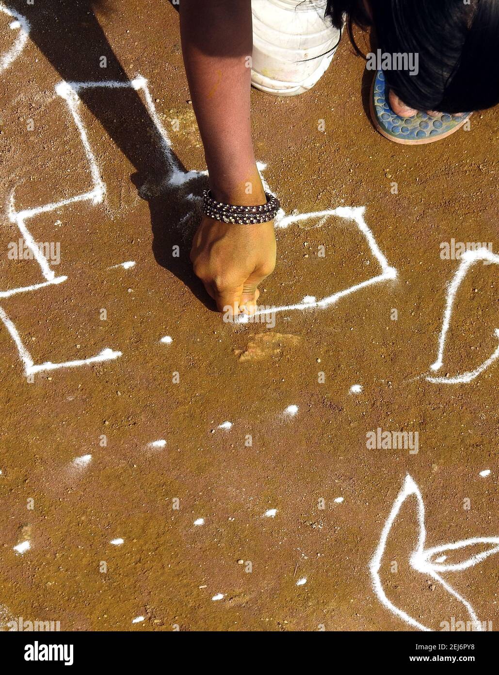 Une femme hindoue indienne dessine des rangoli pendant le festival de récolte pongal or makar sankranti Banque D'Images