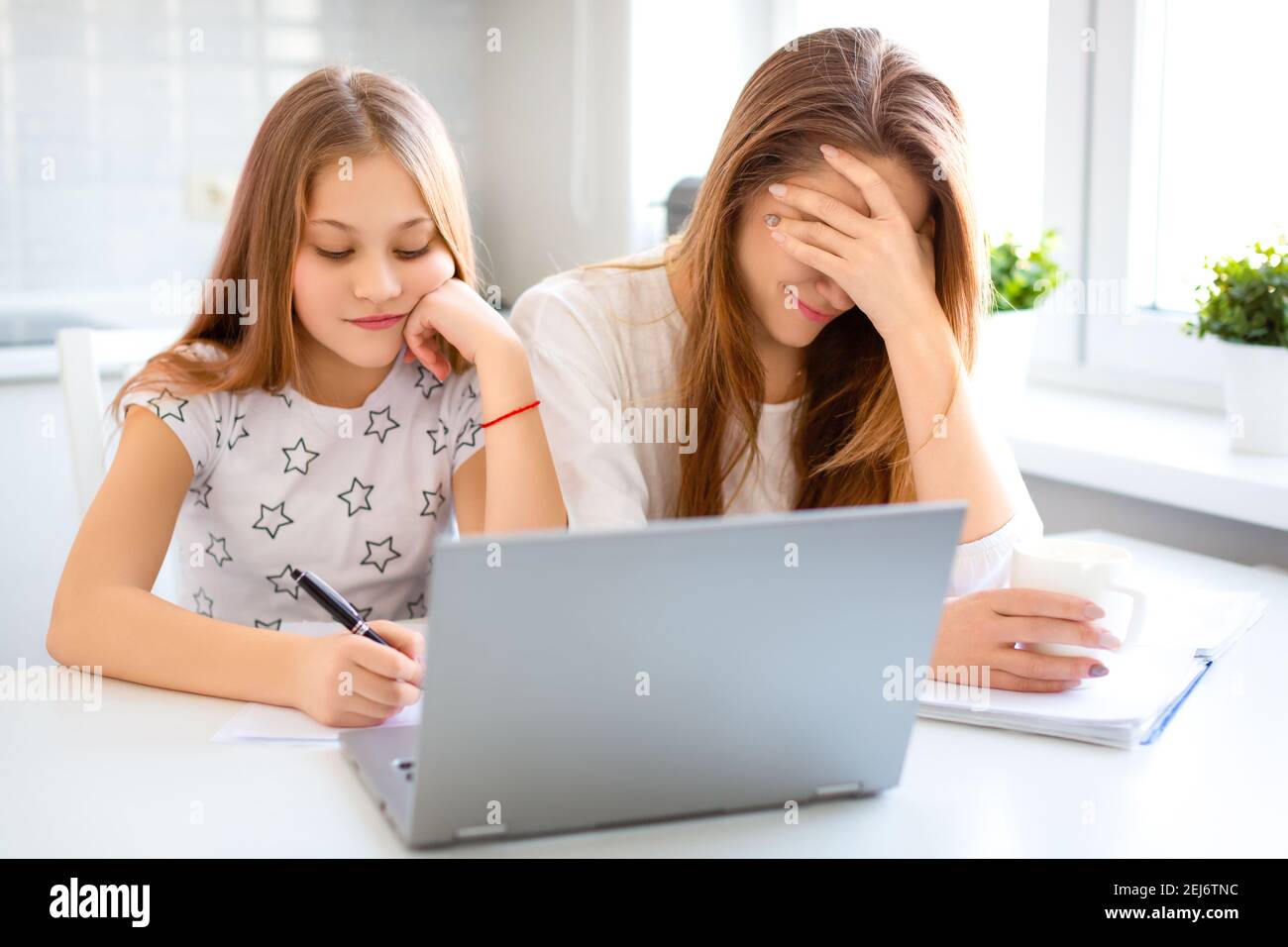 La mère aide son enfant à faire ses devoirs. Maman couvrait le visage de sa main dans la honte pour la stupidité de sa fille. Concept de formation en ligne. Banque D'Images