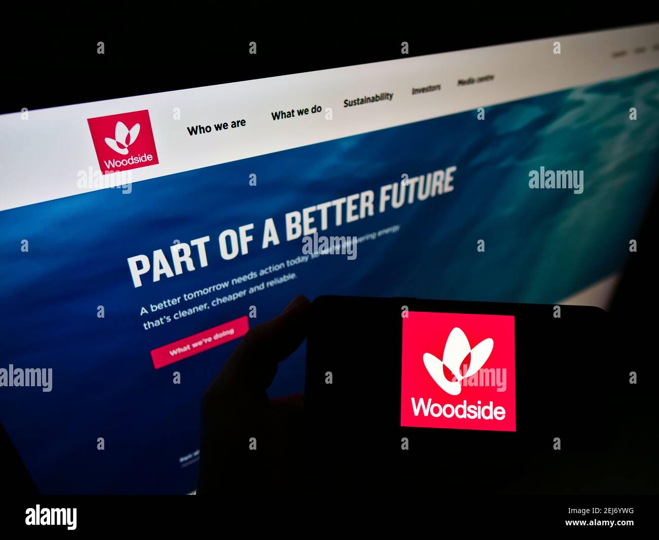 Personne tenant un smartphone avec le logo de la compagnie pétrolière australienne Woodside Petroleum Limited à l'écran devant le site Web. Mise au point sur l'affichage du téléphone. Banque D'Images