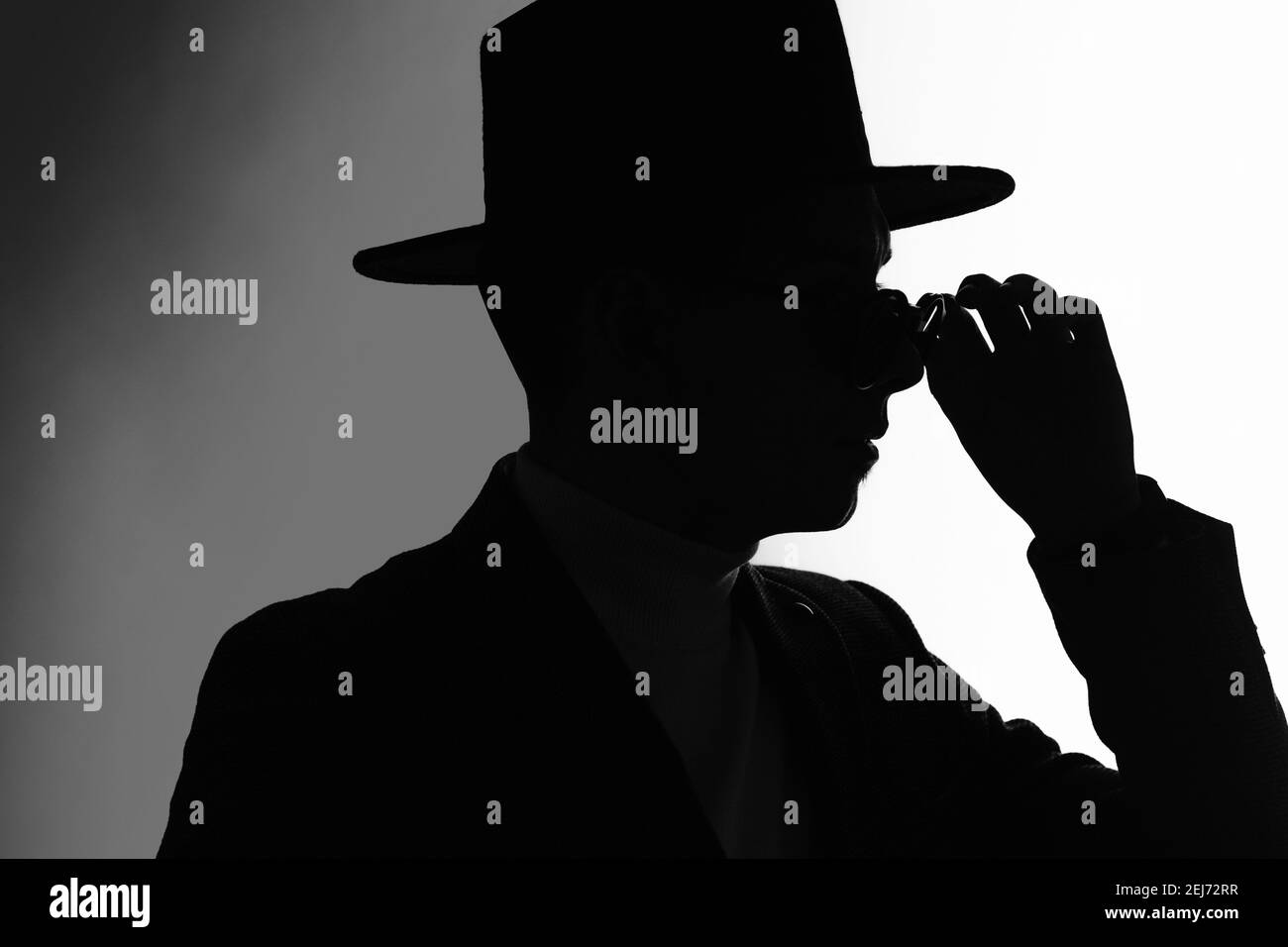 Silhouette d'un homme dans une veste et chapeau classique fixation des  lunettes de soleil Photo Stock - Alamy