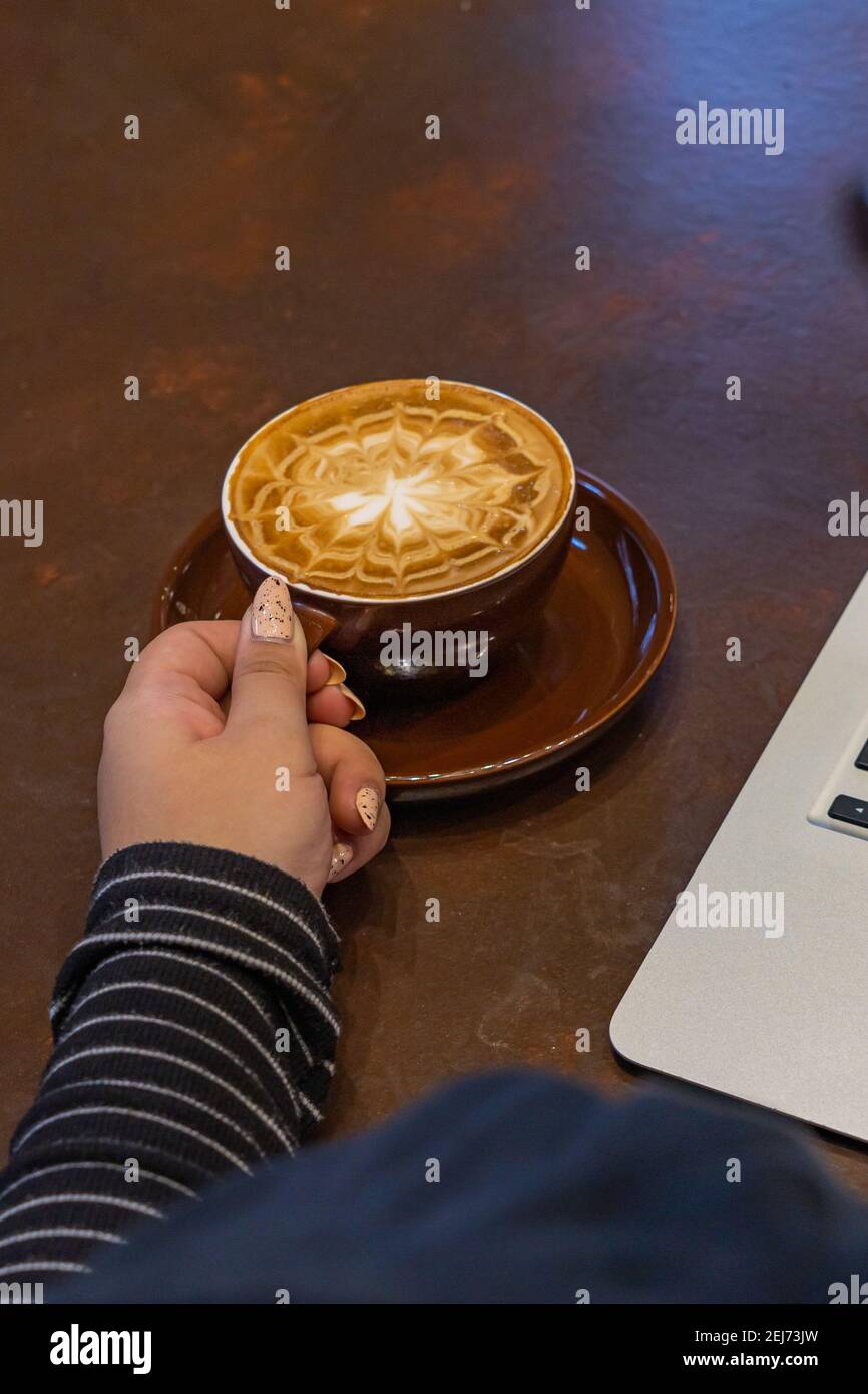 Femme main avec de beaux ongles tenant une tasse de latte. Photo de haute qualité Banque D'Images