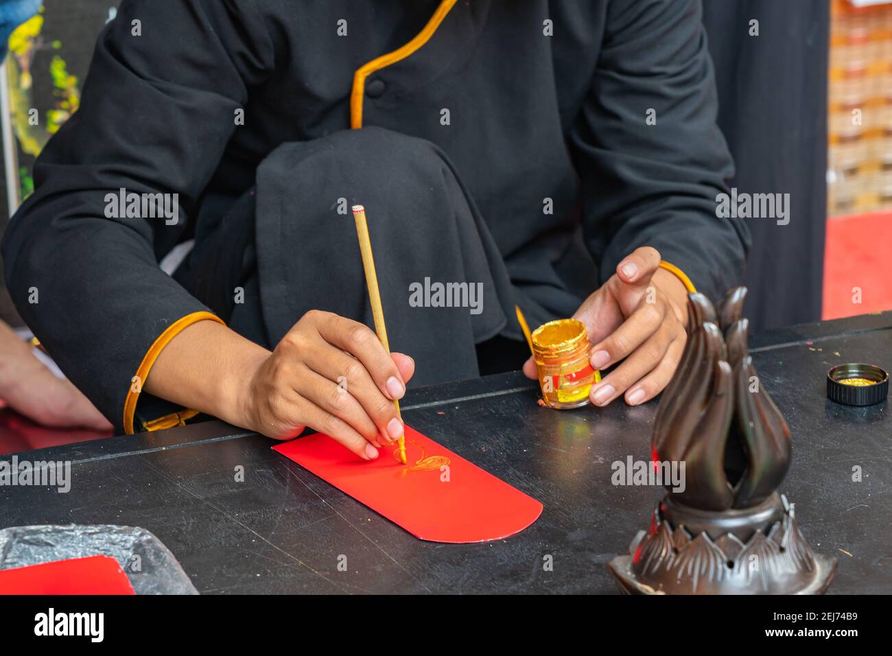 Femme utilisant un stylo à pinceau peinture calligraphie sur l'argent chanceux rouge Enveloppe en vacances Tet Banque D'Images