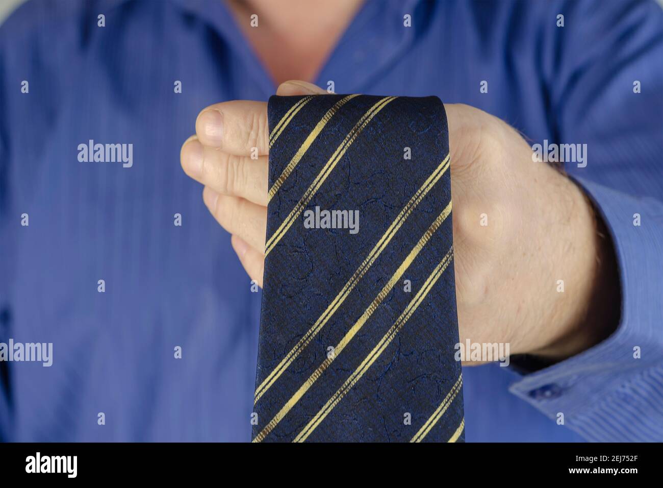 Un homme adulte en chemise bleue noue une cravate. Mains de sexe masculin  avec une cravate bleue et une bande jaune. Étape par étape. Mise au point  sélective Photo Stock - Alamy