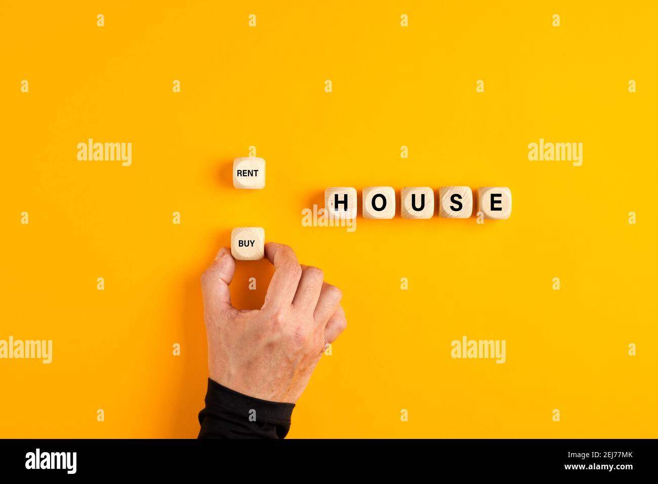 La maison de mot sur des blocs de bois avec une main mâle choisissant l'option d'achat. Décider d'acheter un bien immobilier. Banque D'Images