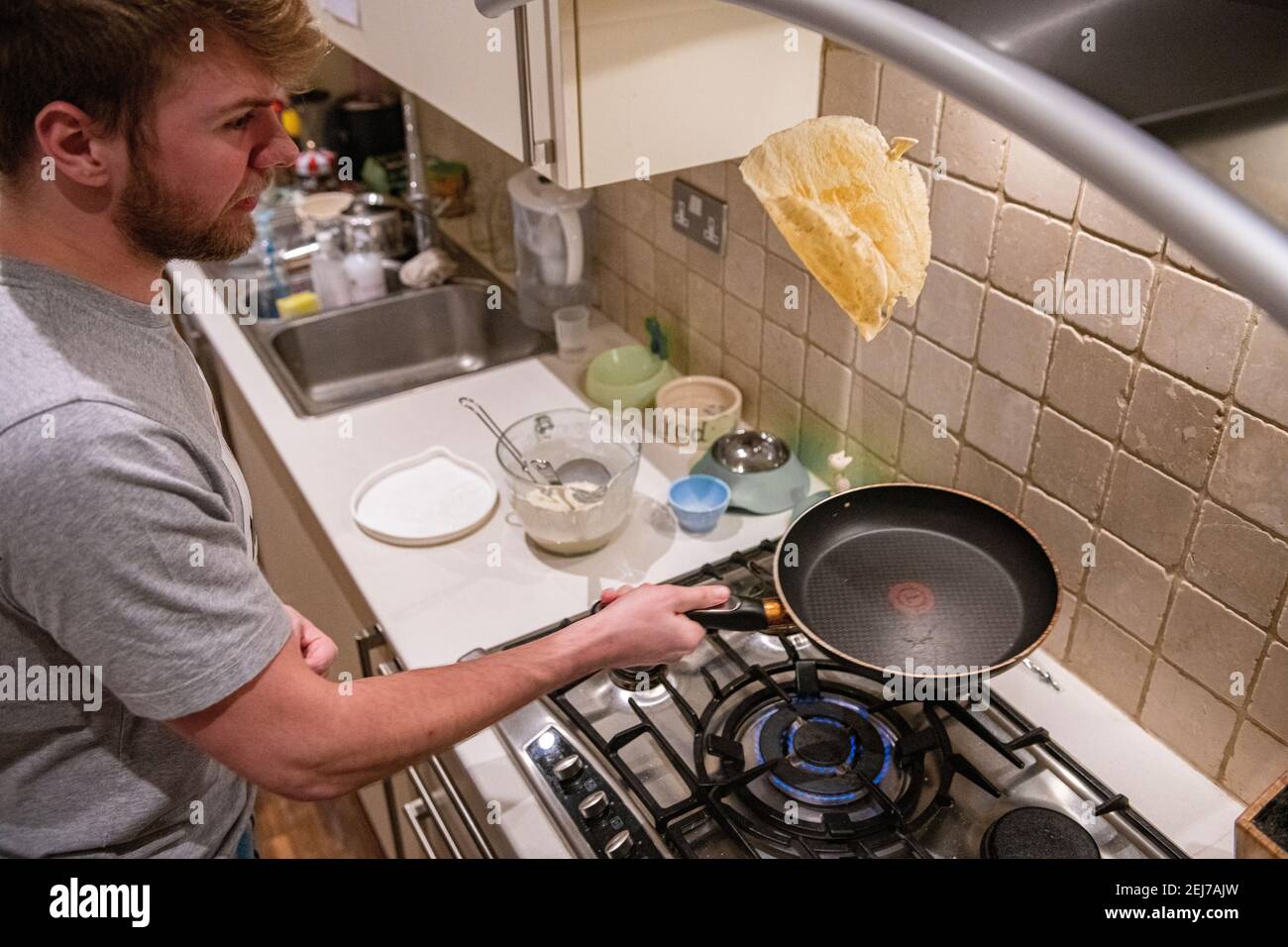 Un adolescent lance une crêpe le jour de la crêpe, Shrove Tuesday Banque D'Images