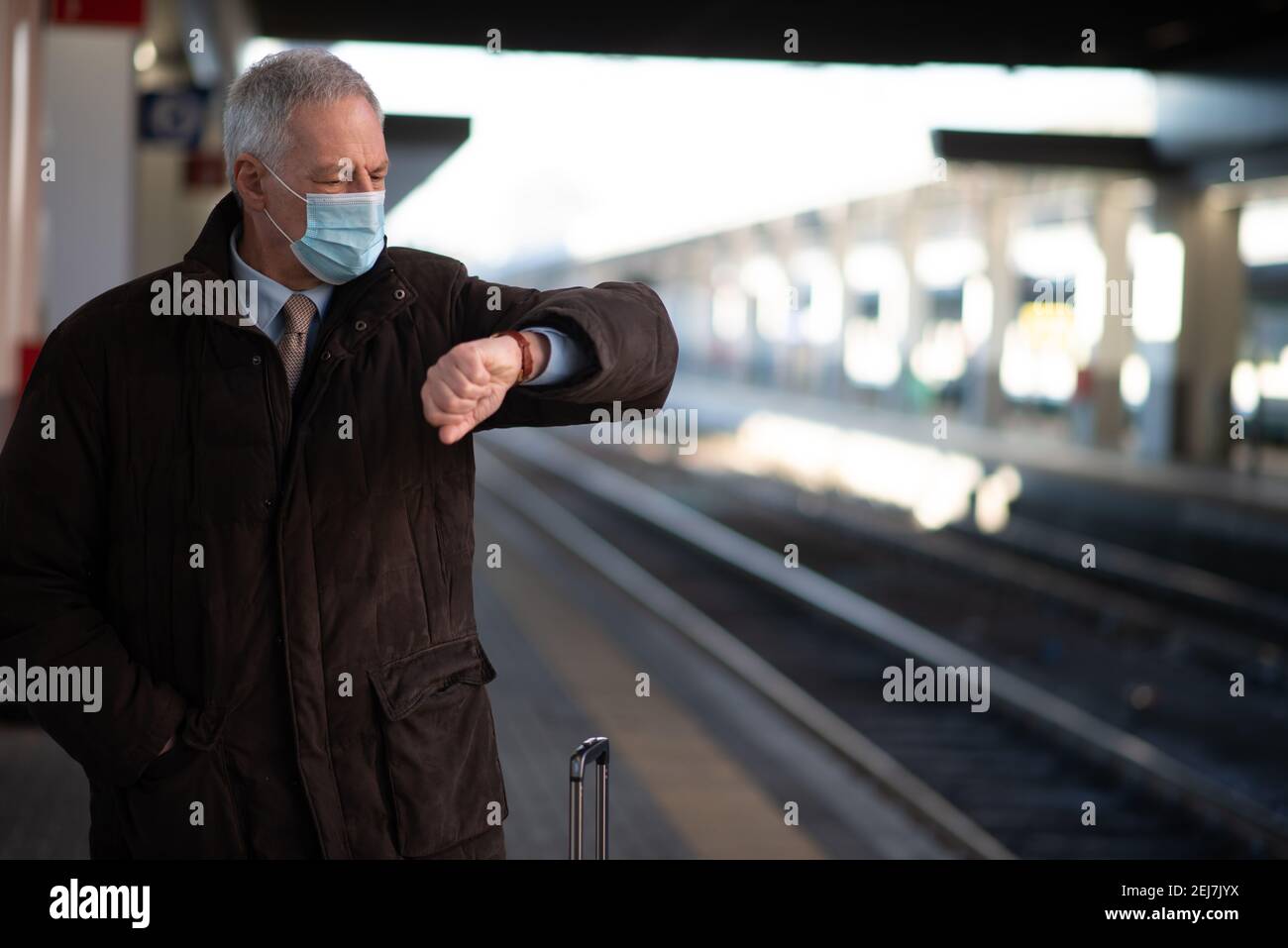 Homme d'affaires senior masqué attendant le concept de mobilité du train, du covid et du coronavirus Banque D'Images